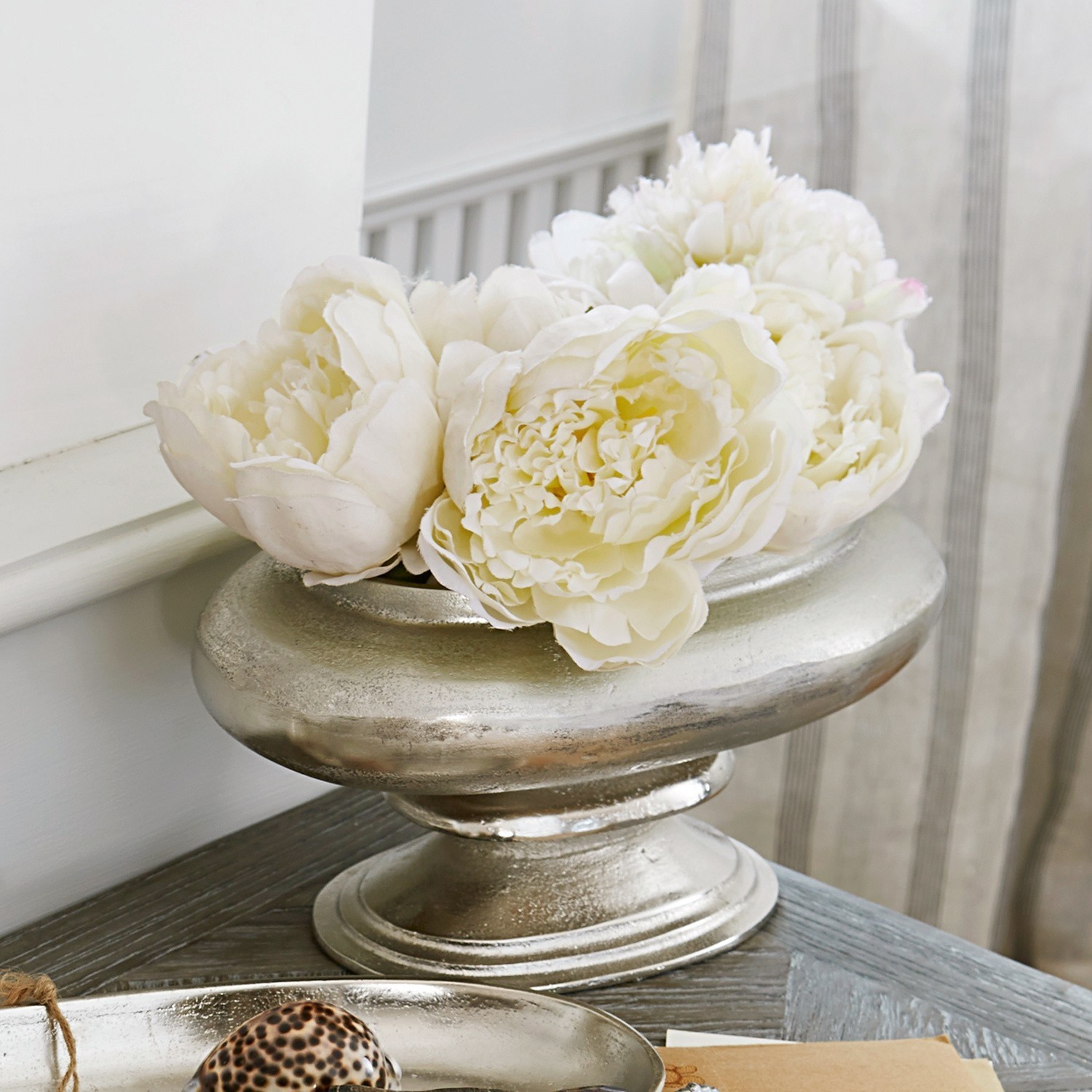 Stříbrná kovová dekorativní mísa s bílými květy na dřevěném stole v obývacím pokoji