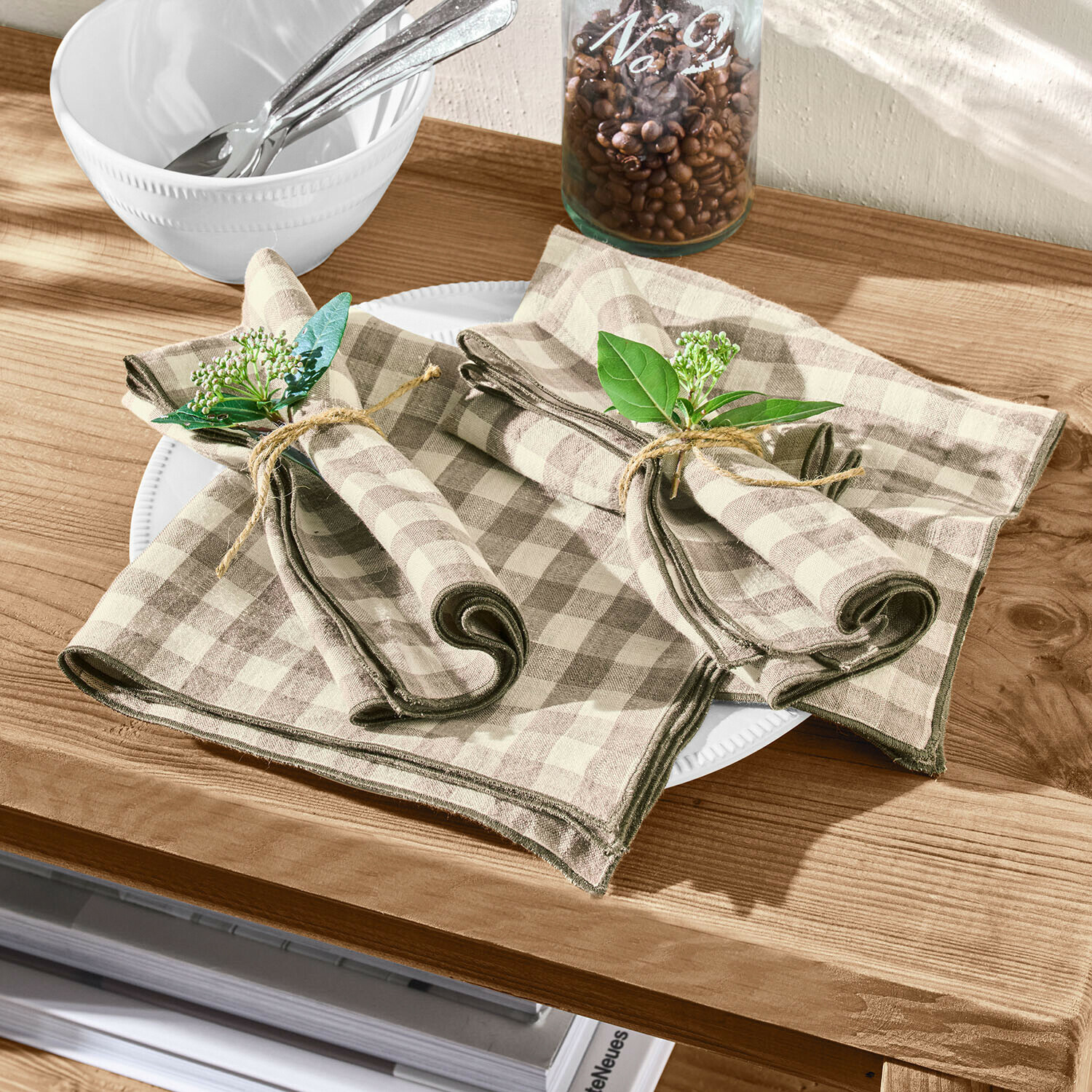 Lněné béžovo-hnědé kostkované ubrousky se zelenými větvičkami na dřevěném stole