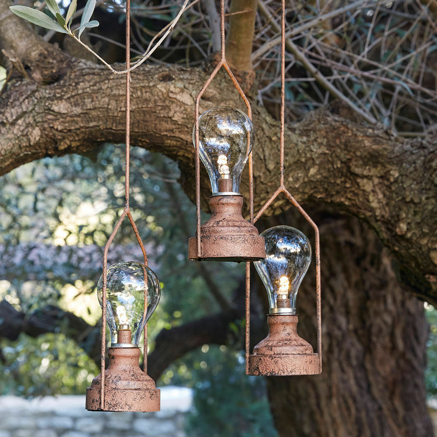 Závěsné LED lucerny, 3dílná sada Chambéry Tři závěsné lampy z rezavého kovu s LED žárovkami před stromem, dekorativní venkovní osvětlení