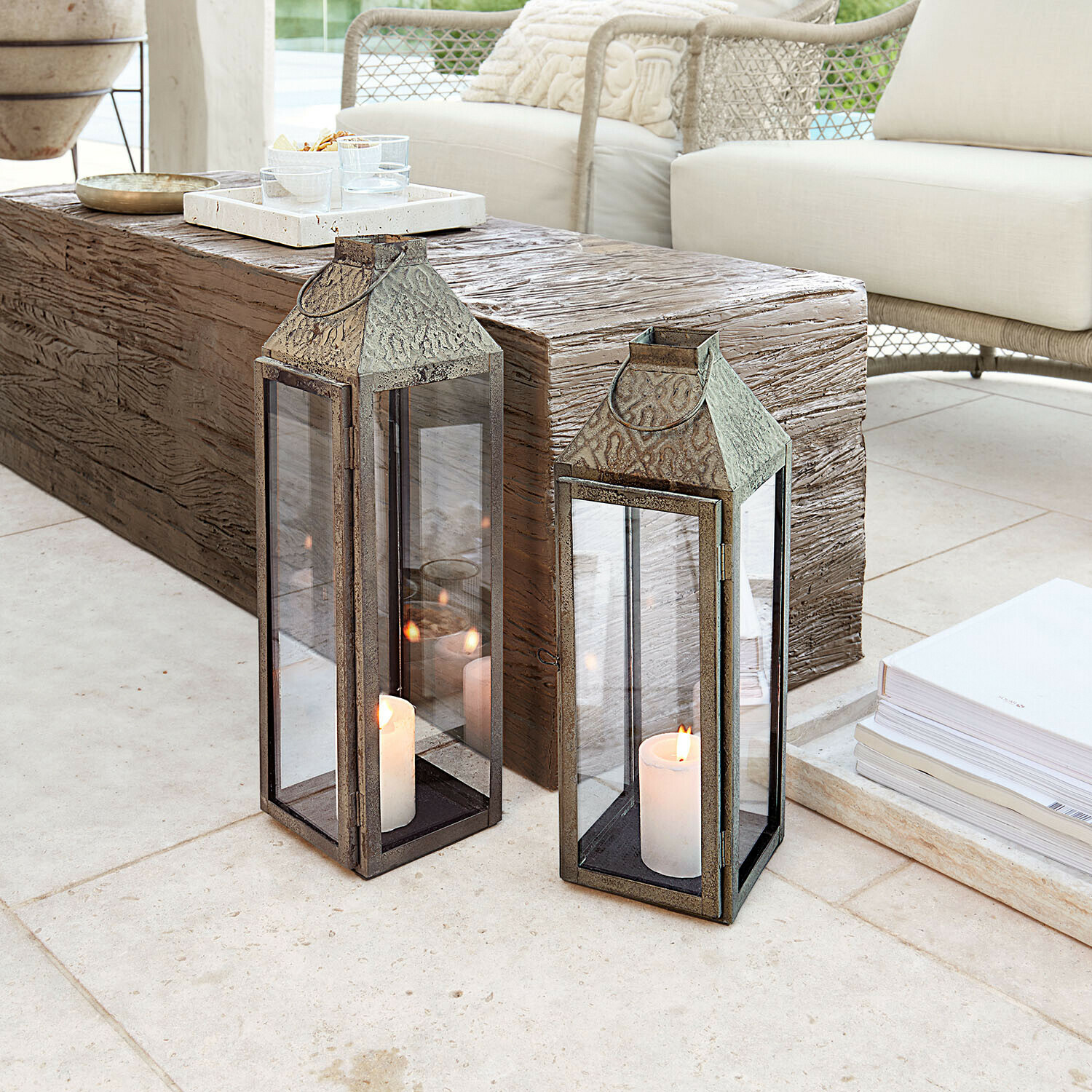 Dvě kovové lucerny se svíčkami na světlé podlaze v moderním obývacím pokoji