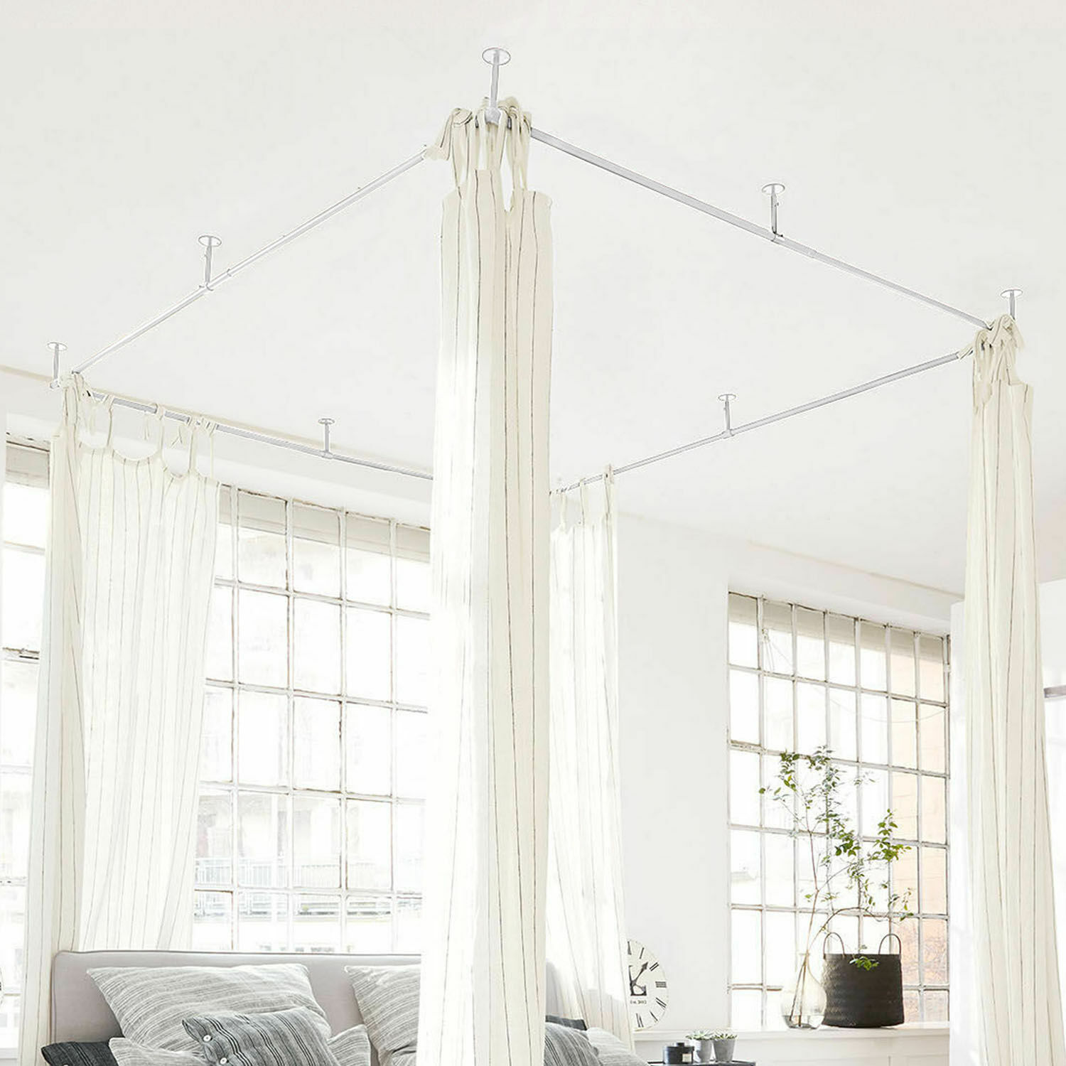 Bílé závěsy s tenkými pruhy na kovovém stropním rámu v světlém moderním interiéru