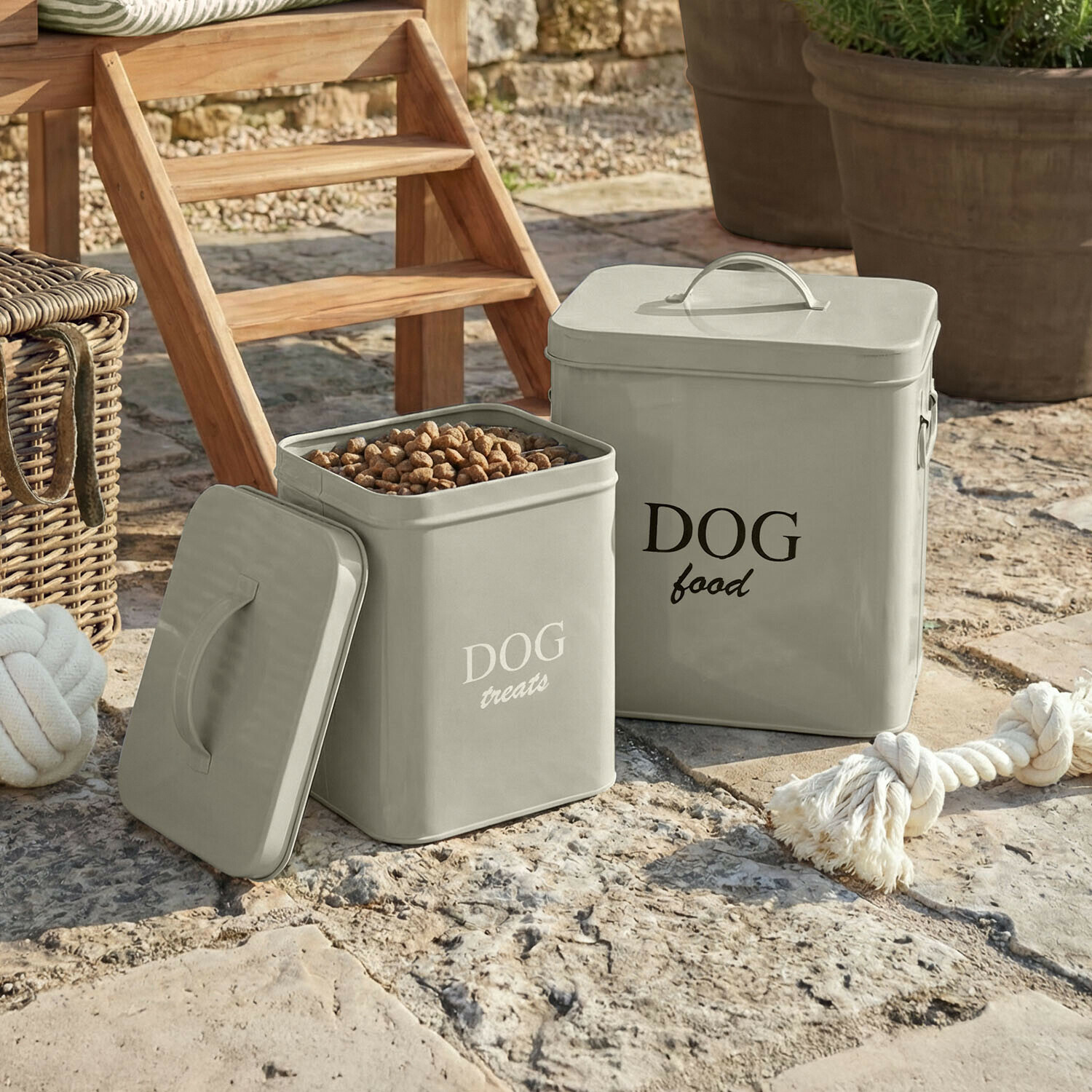 Šedé kovové nádoby na psí jídlo a pamlsky na kamenné podlaze venku