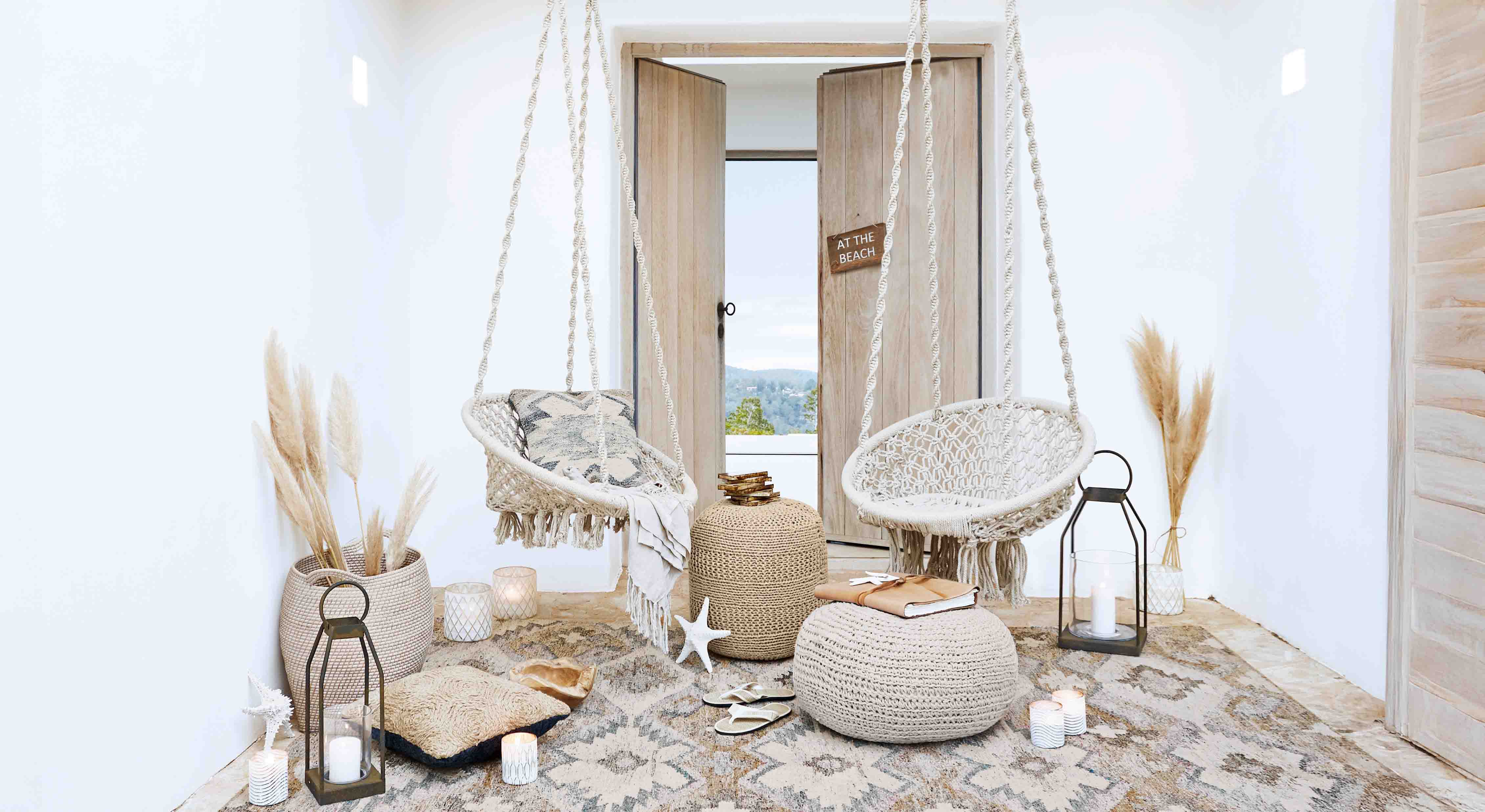Pohodlný obývací pokoj s bílými závěsnými křesly z makramé a přírodními dekoracemi v boho stylu