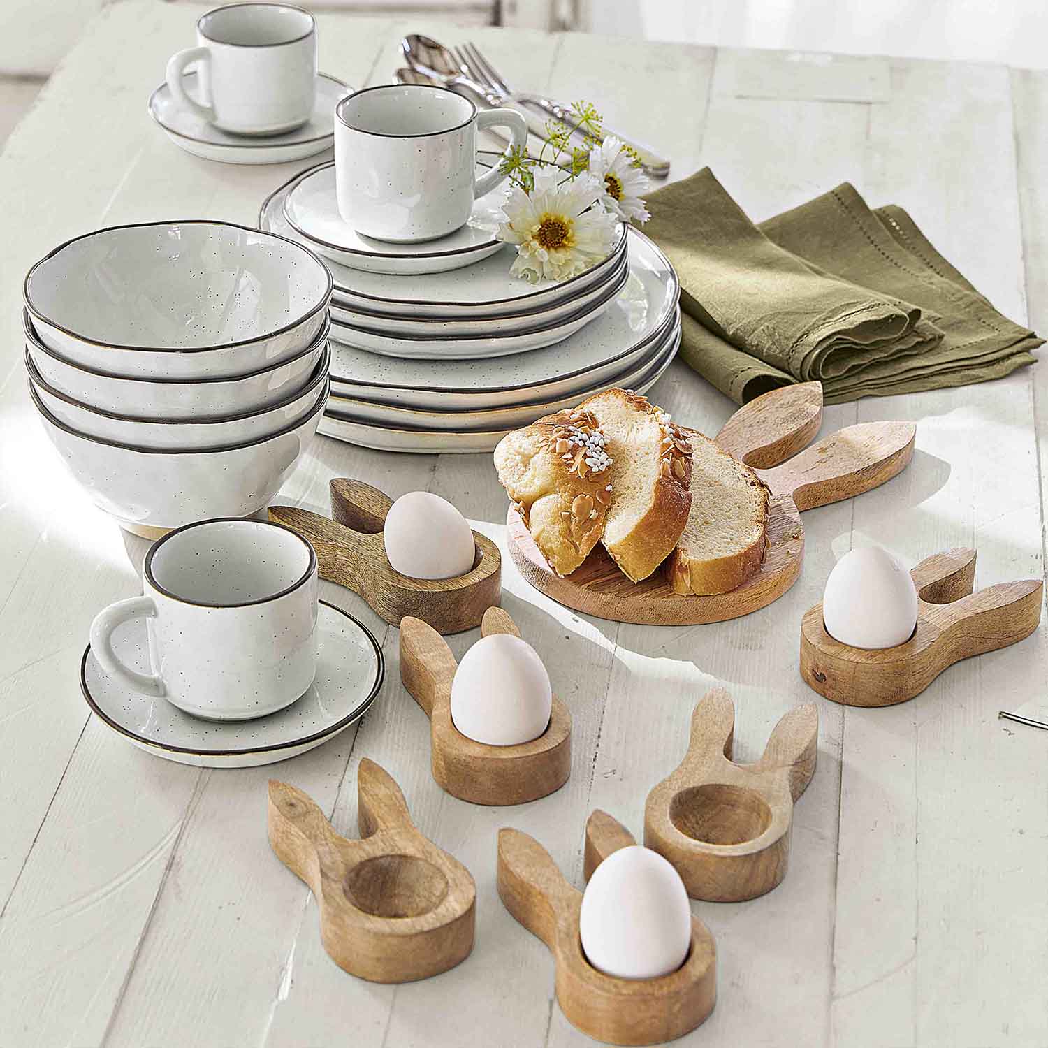 Bílý keramický jídelní servis s hnědým okrajem a dřevěnými stojánky na vejce ve tvaru zajíce