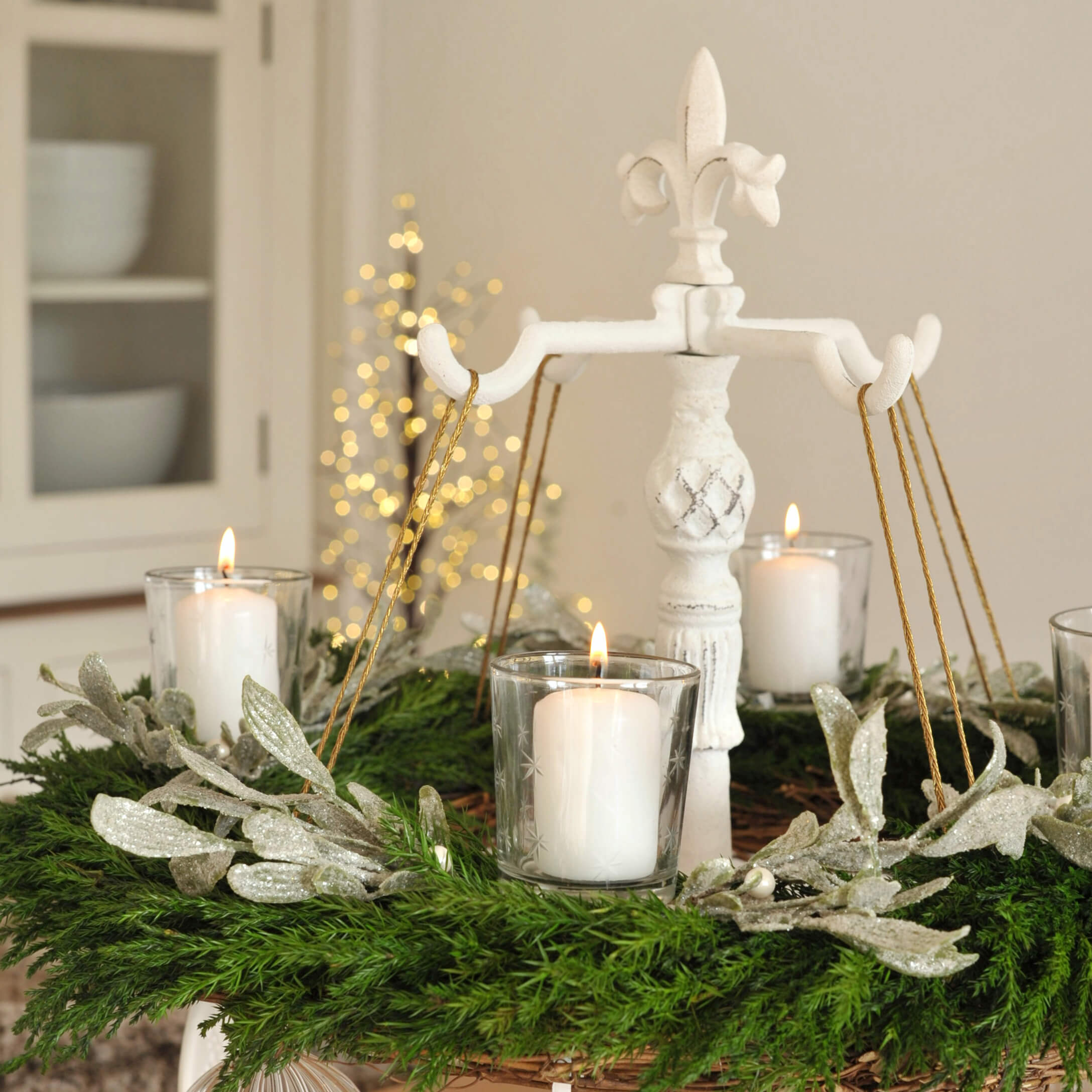 Bílý kovový adventní věnec se zeleným věncem a bílými svíčkami pro vánoční výzdobu