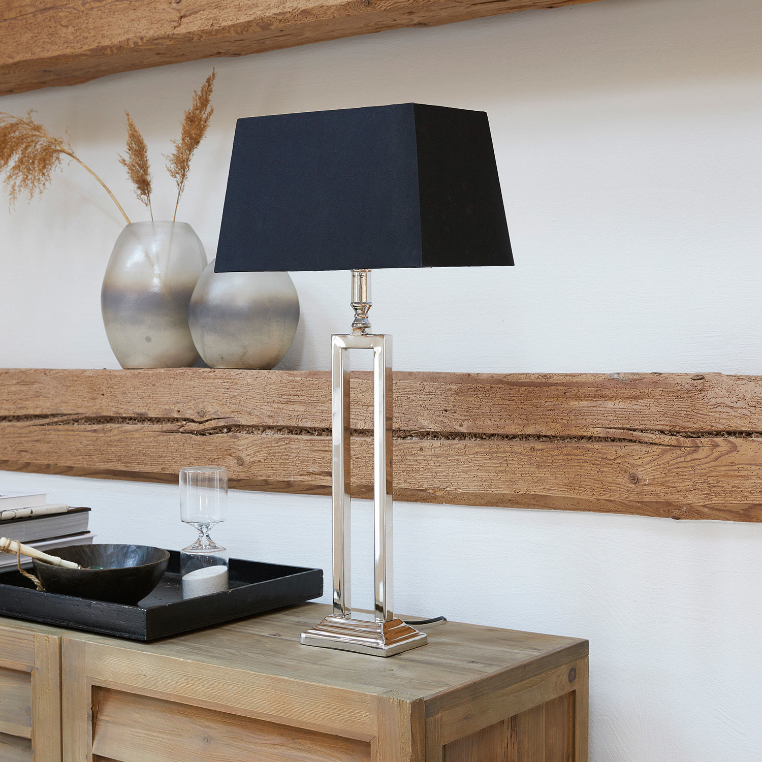 Stolní lampa Kinshaa Elegantní stolní lampa s kovovým podstavcem a černým stínidlem na dřevěném stole
