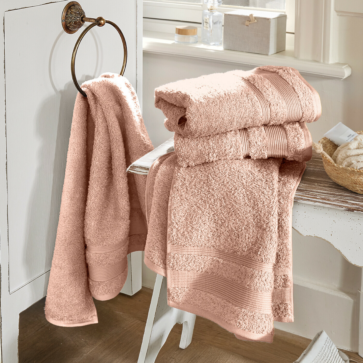 Růžové bavlněné koupelnové ručníky na bílém nábytku v světlé koupelně, měkké a savé
