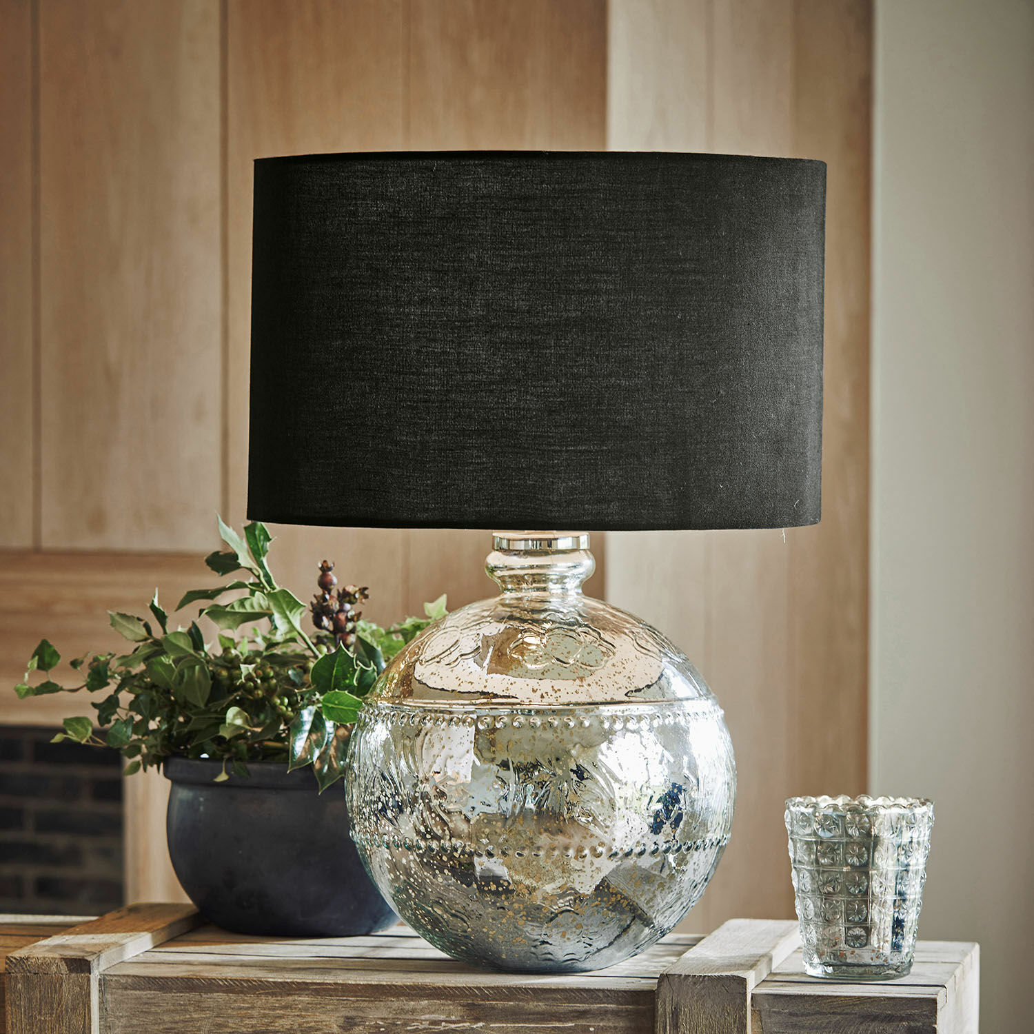 Stolní lampa Voyer Dekorativní stolní lampa se stříbrným skleněným tělem a černým stínidlem na dřevěném stole