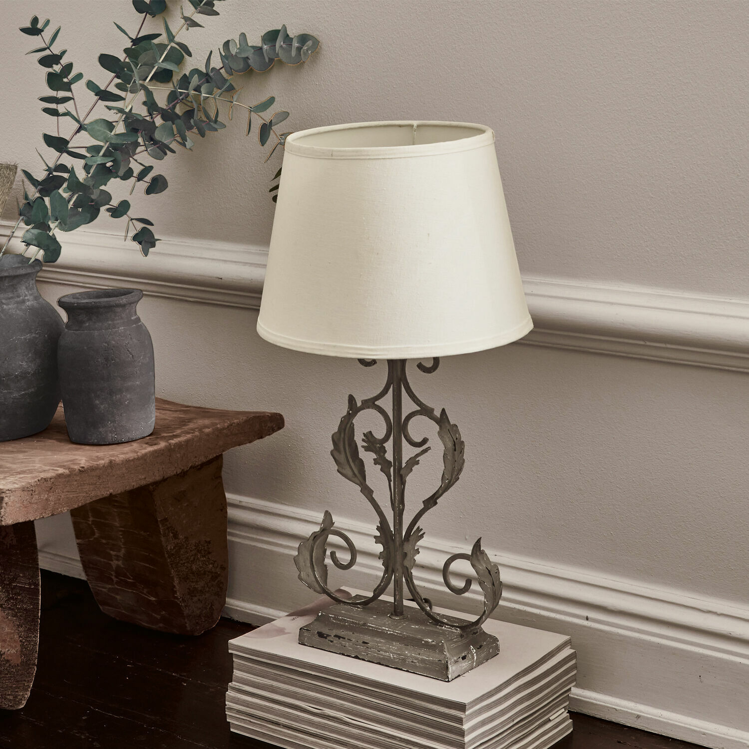 Stolní lampa Chanéac Stolní lampa se šedou kovovou základnou a krémovým stínidlem na dřevěné podlaze