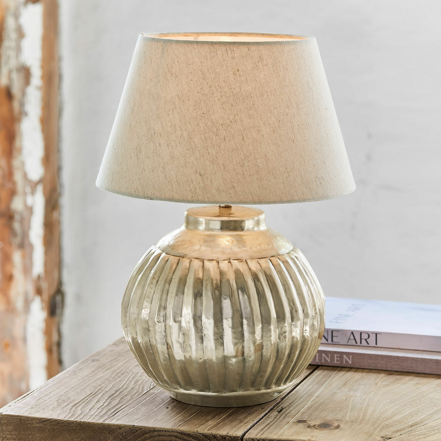 Stolní lampa Lillemor Stolní lampa z mosazi s béžovým stínidlem na dřevěném stole, interiérová dekorace