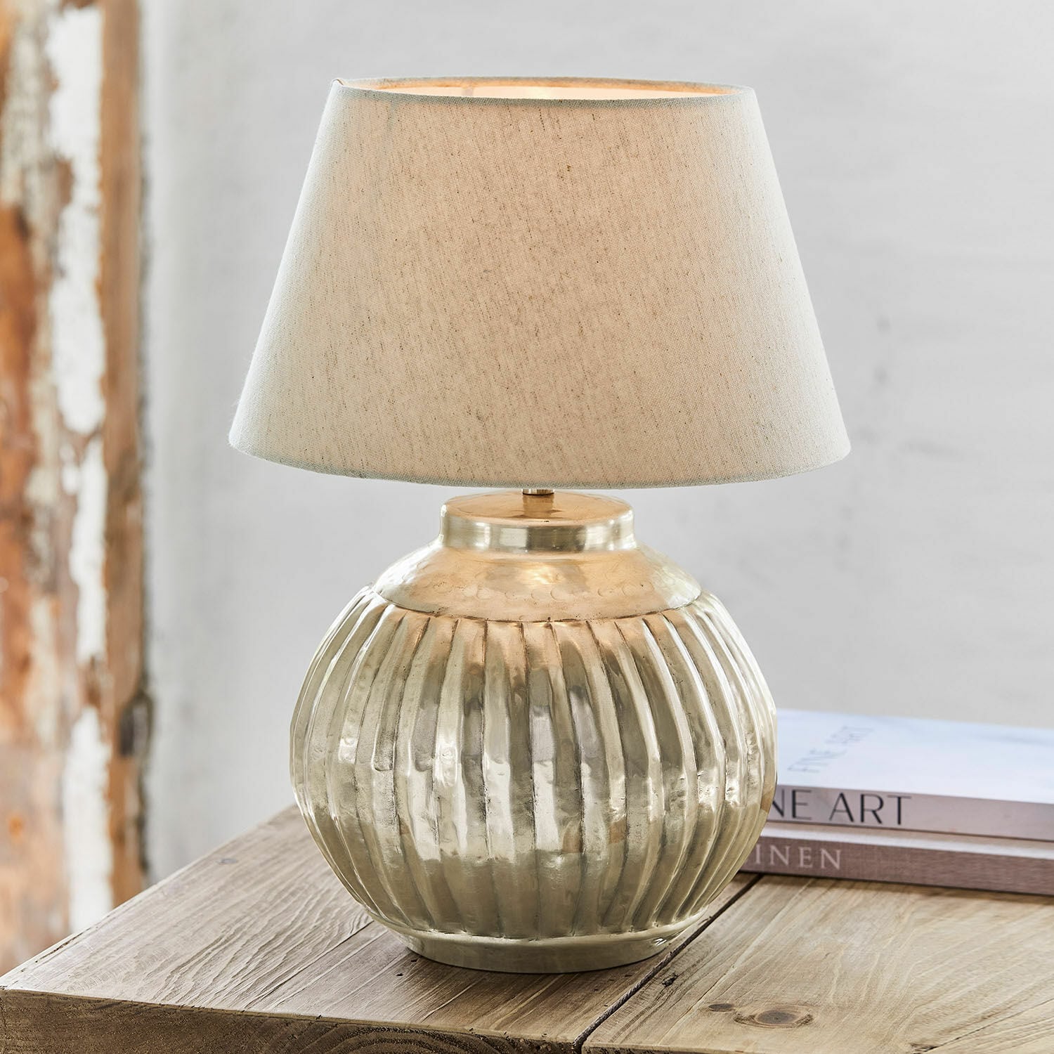 Stolní lampa Lillemor Stolní lampa z mosazi s béžovým stínidlem na dřevěném stole, interiérová dekorace