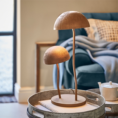 Dřevěná stolní lampa ve tvaru houby v přírodní barvě na kovovém podnosu v obývacím pokoji