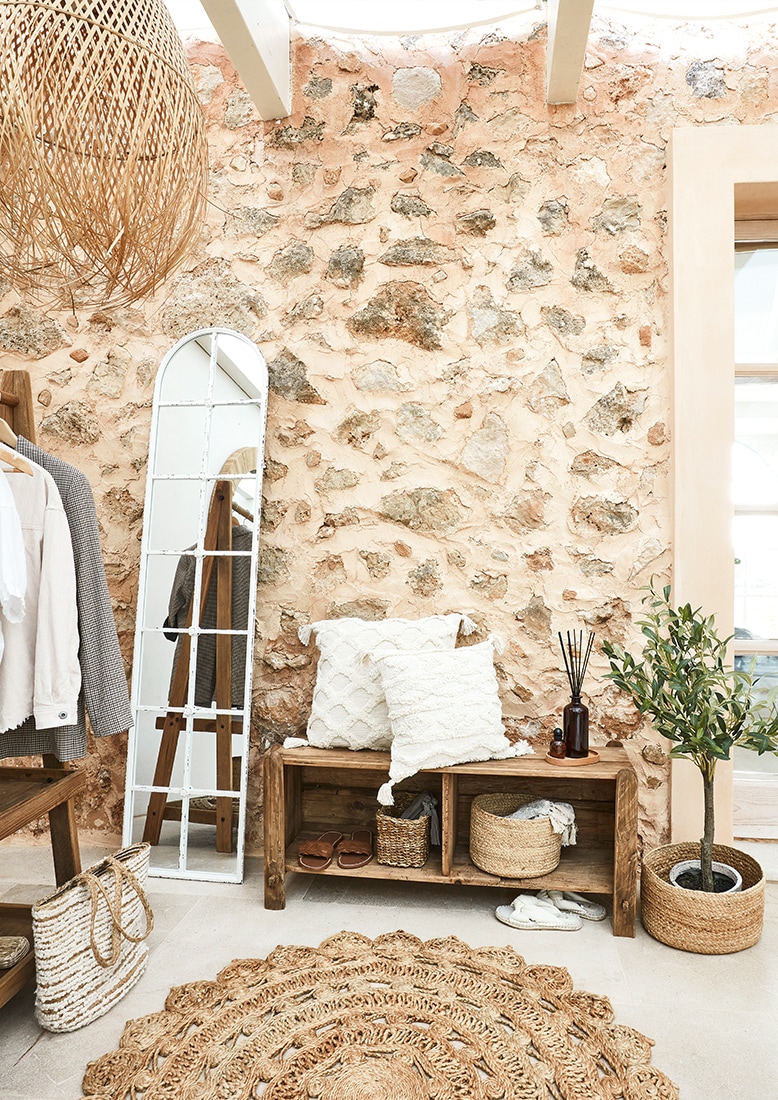 Příjemný kout s dřevěnou lavicí, bílými polštáři a přírodním jutovým kobercem v boho stylu