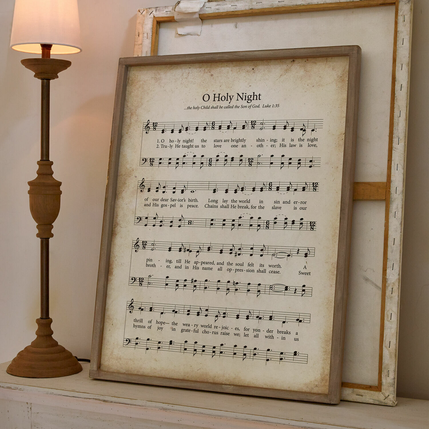 Obraz Holy Night Obraz s notami a textem písně O Holy Night v dřevěném rámu vedle lampy
