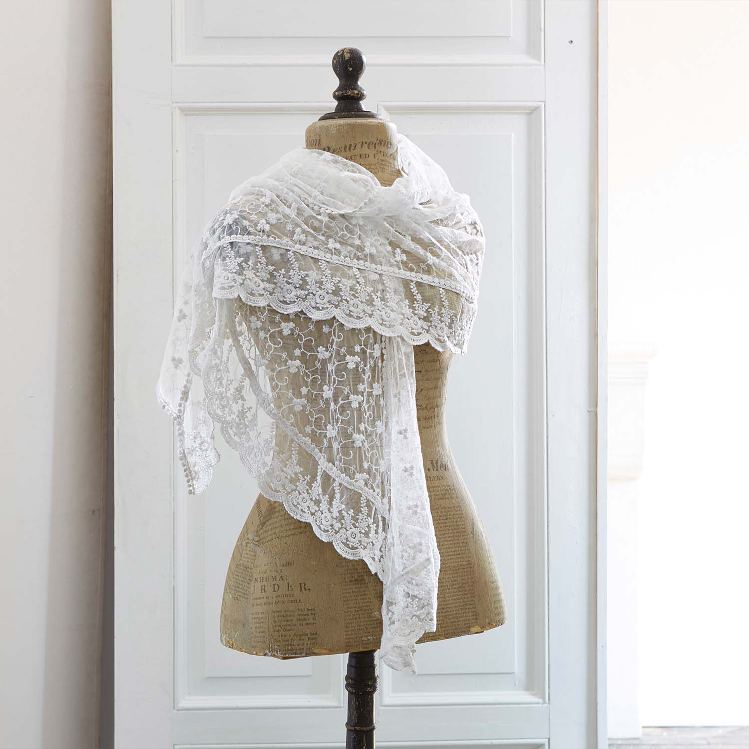 Jemný bílý krajkový šátek s květinovým vzorem na figuríně, elegantní módní doplněk