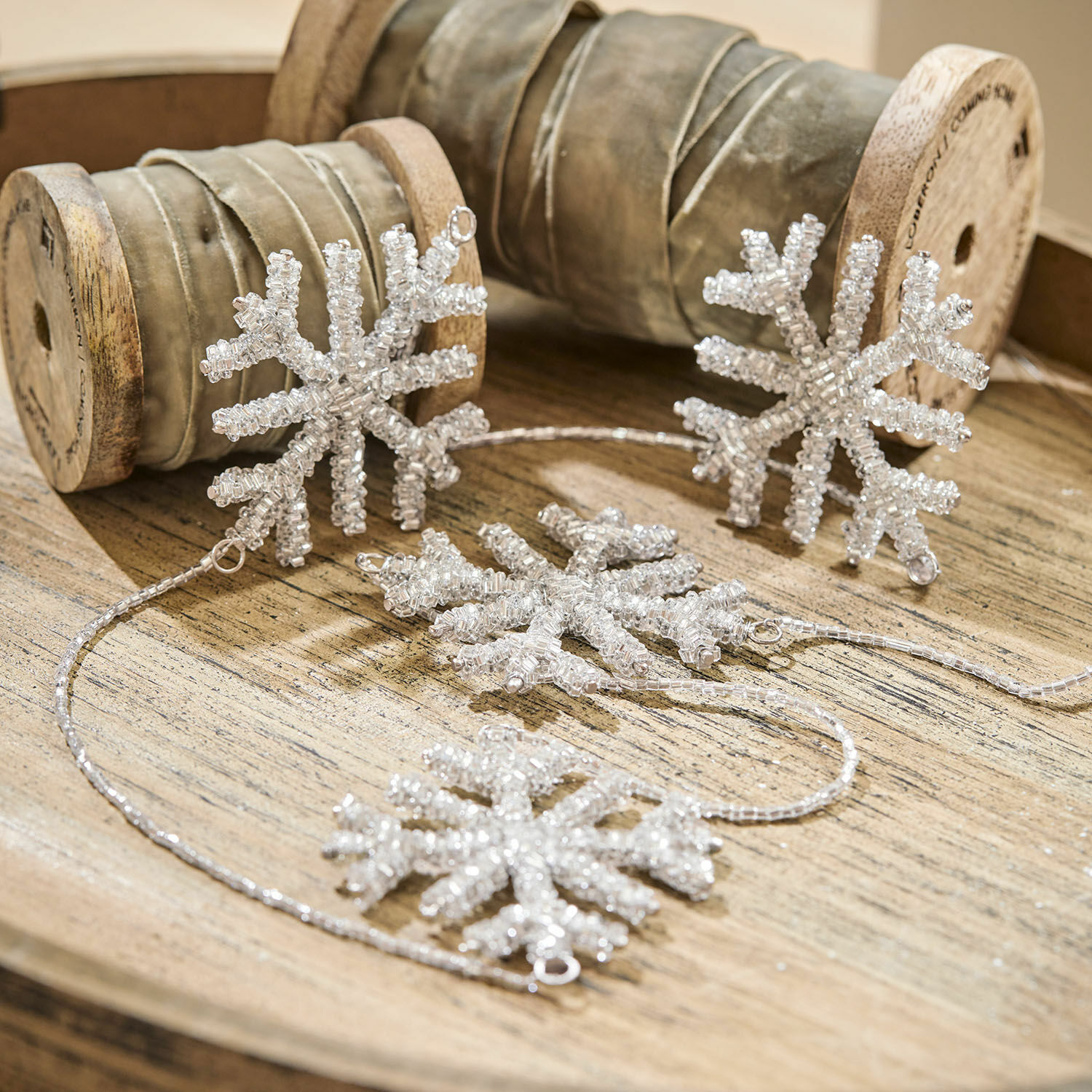 Girlanda Snowflakes Dekorativní řetěz z průhledných korálků ve tvaru sněhových vloček na dřevěném podnosu
