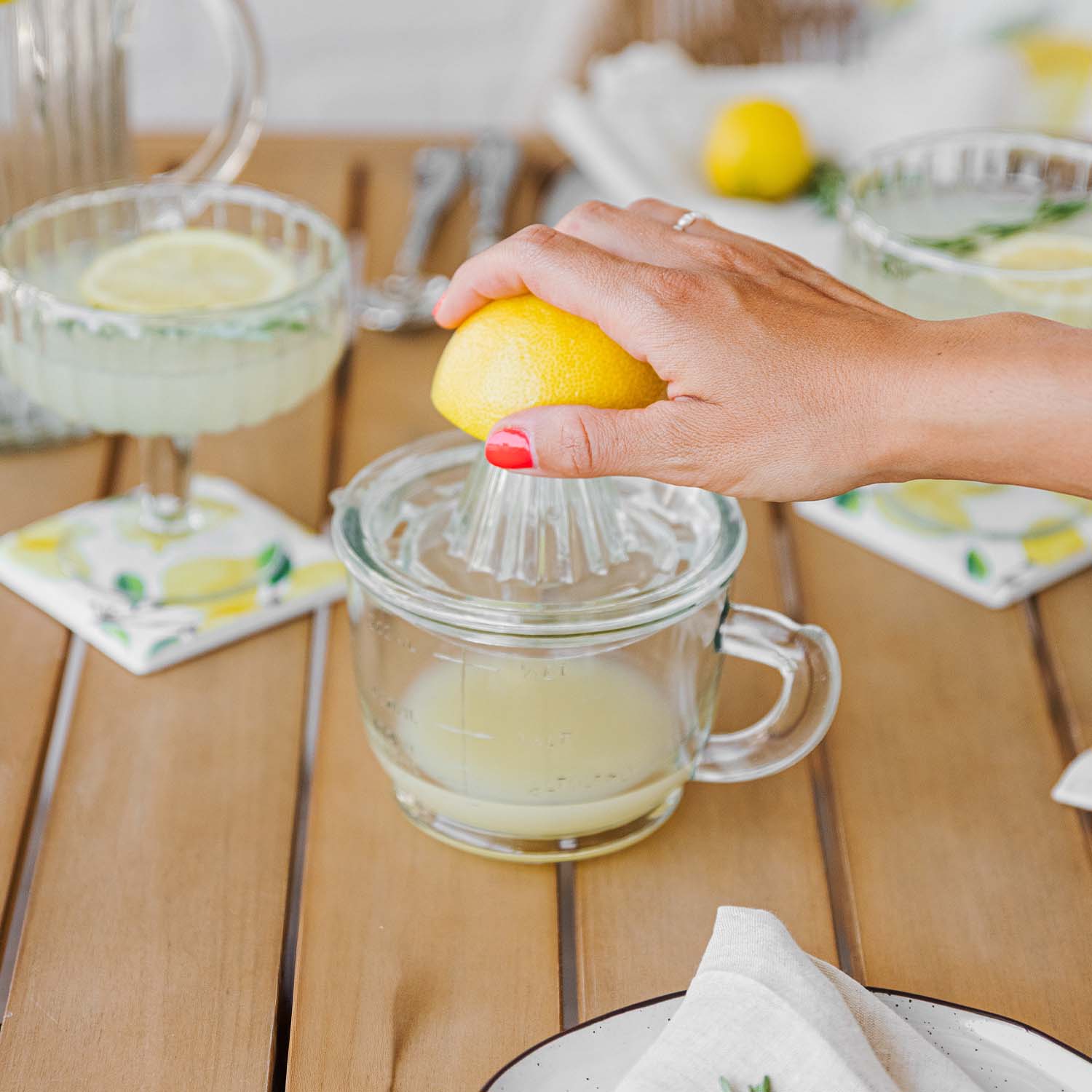 Ruka mačká žlutý citron na skleněné odšťavňovači na dřevěném stole s citronovými nápoji