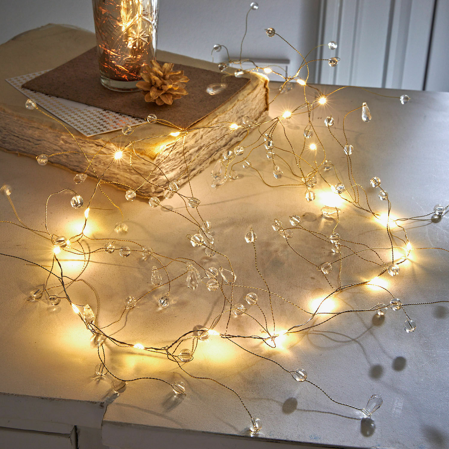 Jemný světelný řetěz s průhlednými krystaly na zlatém drátě, elegantní stolní dekorace