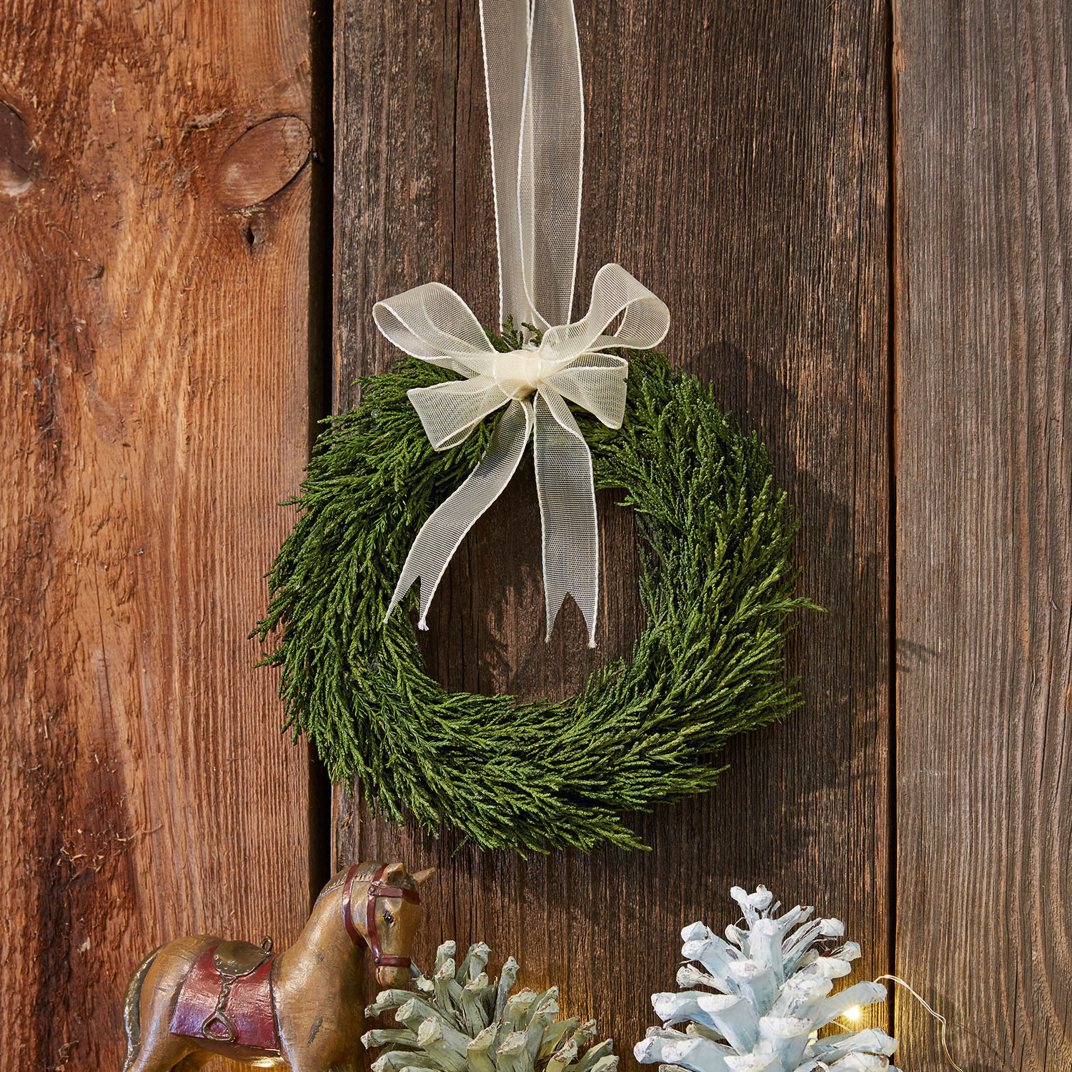Věnec Sare Zelený věnec z větviček s krémovou mašlí na dřevěném pozadí, vánoční dekorace