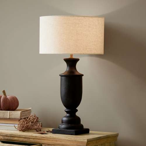 Černá keramická stolní lampa s béžovým stínidlem na dřevěném stole, interiérová dekorace