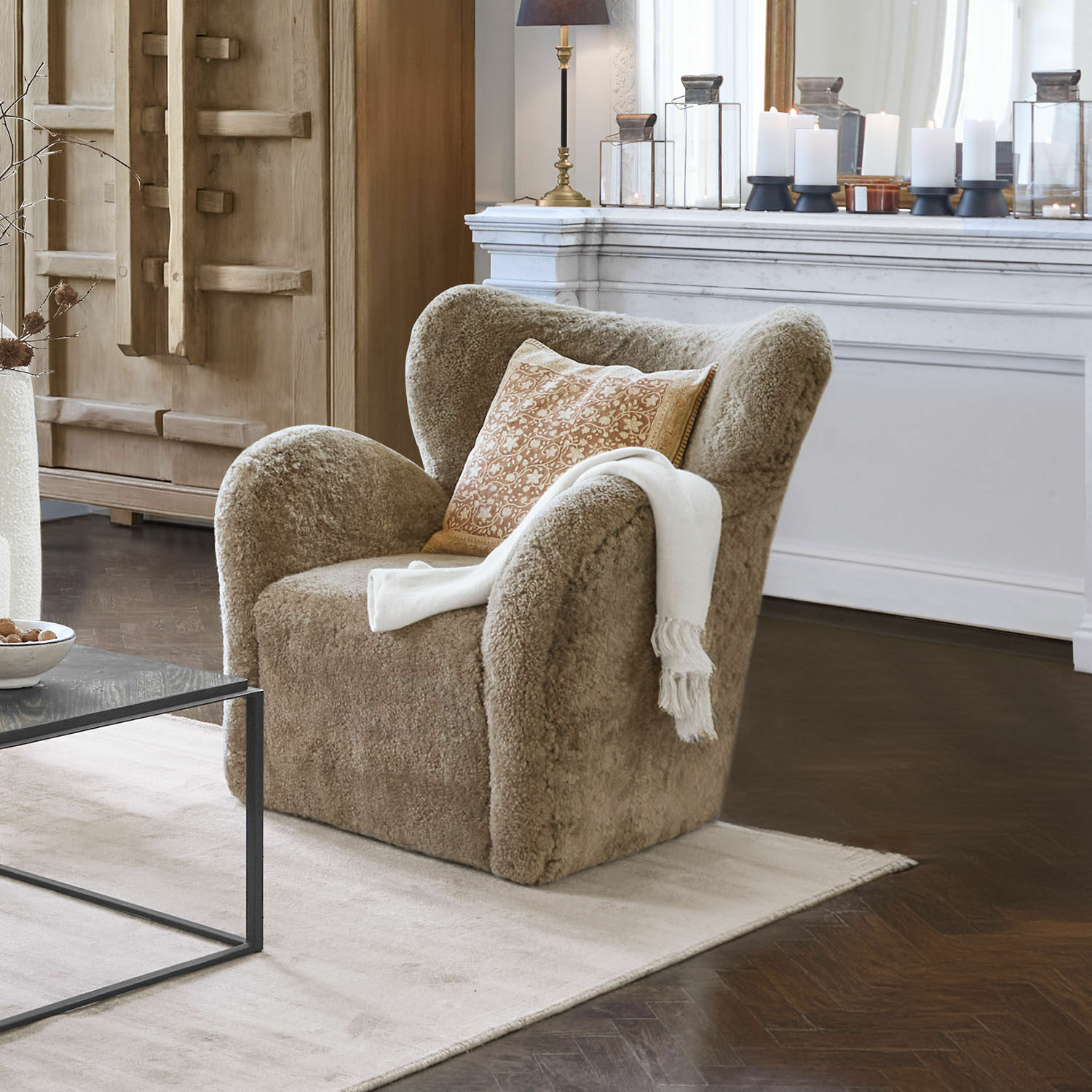 Křeslo Ambrécourt Béžové křeslo z měkkého materiálu s polštářem a bílou dekou v elegantním obývacím pokoji