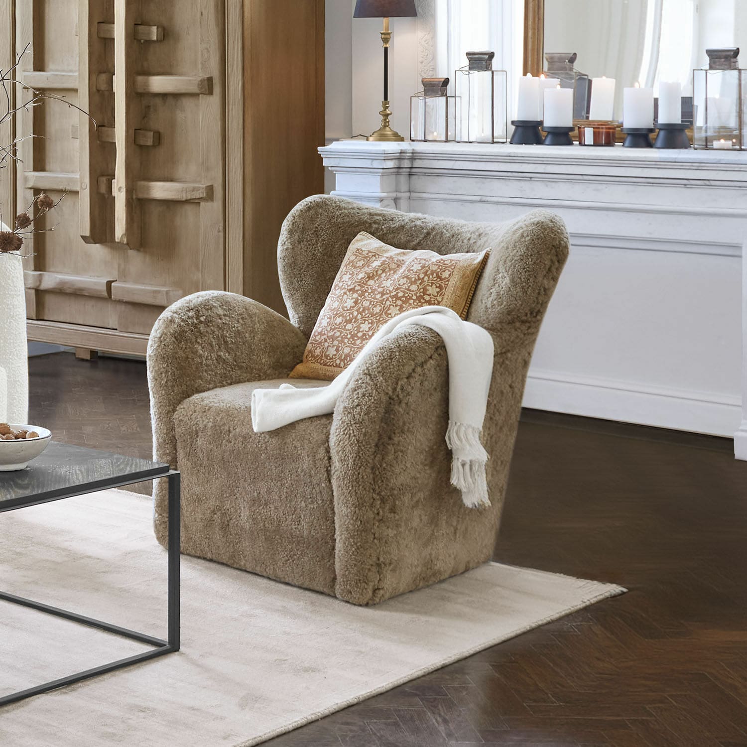 Křeslo Ambrécourt Béžové křeslo z měkkého materiálu s polštářem a bílou dekou v elegantním obývacím pokoji