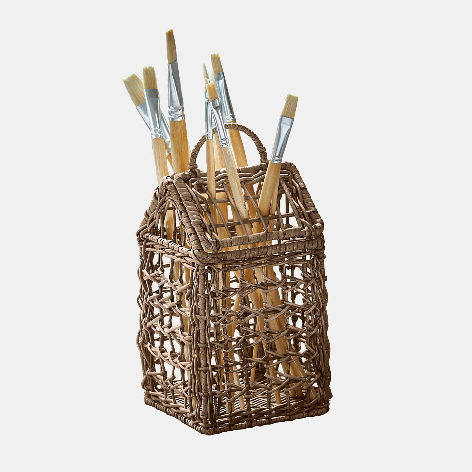 Hnědý proutěný košík ve tvaru domu s malířskými štětci s dřevěnými rukojeťmi