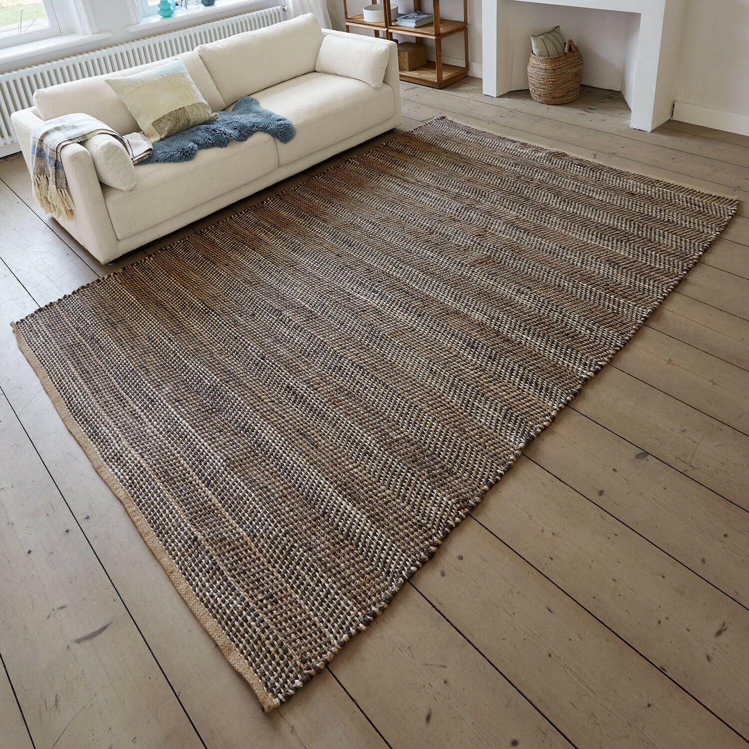 Koberec Myråsen Koberec z přírodního materiálu v hnědo-béžových odstínech na dřevěné podlaze v obývacím pokoji