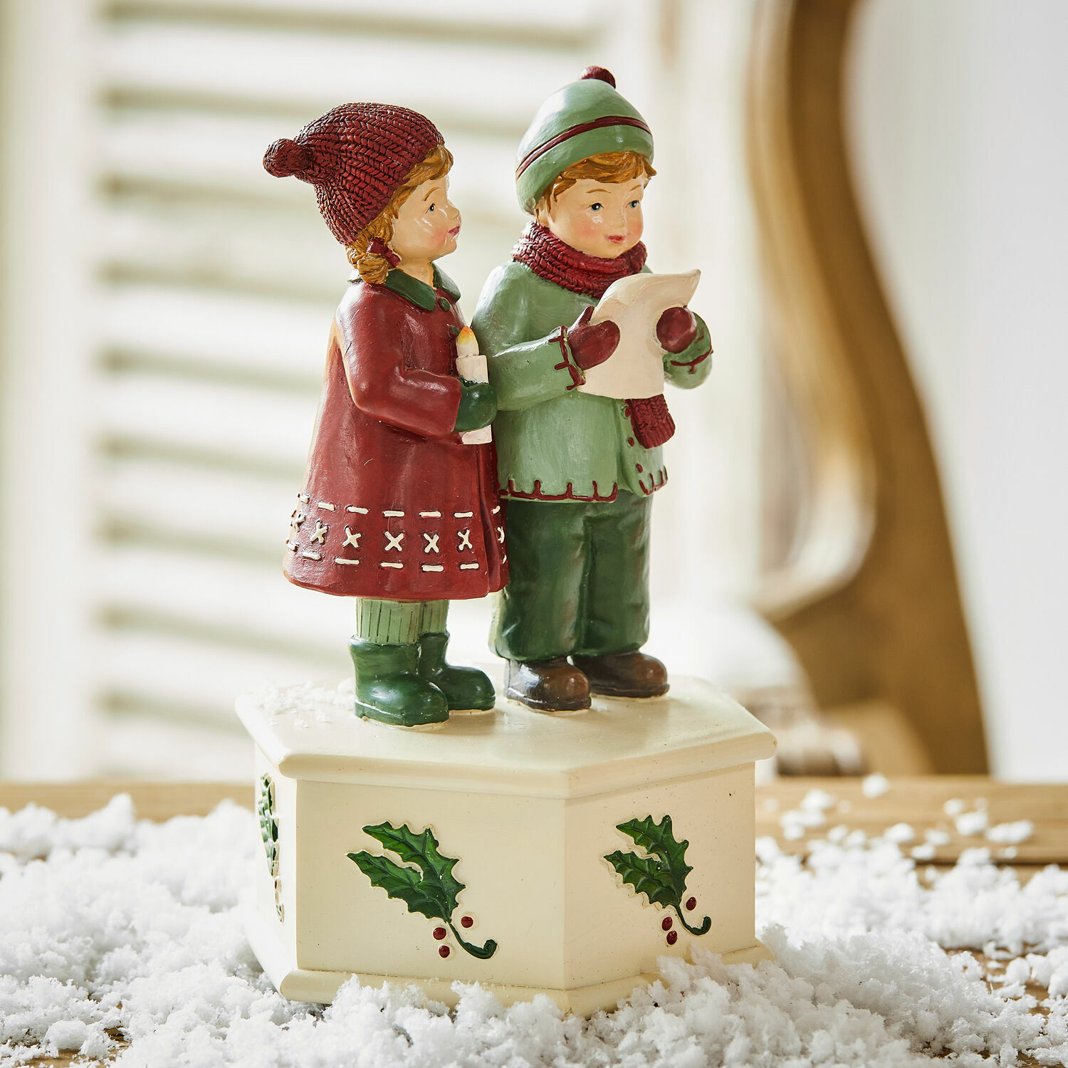 Figurka dětí zpívajících koledy na krémovém podstavci s motivem cesmíny, vánoční dekorace