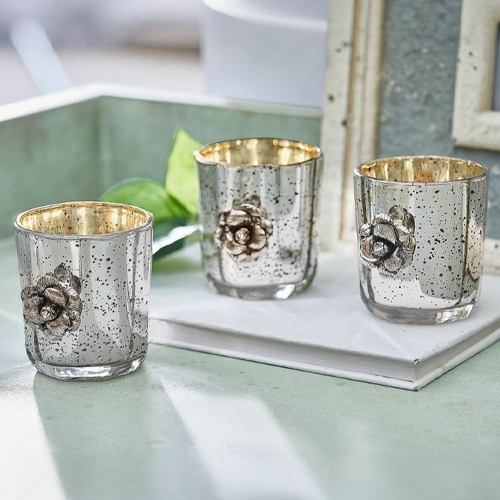 Sada tří skleněných svícnů s kovovým povrchem a růžovou ozdobou, elegantní stolní dekorace