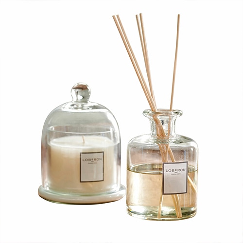 Skleněný aroma difuzér a svíčka pod skleněným poklopem v neutrálních barvách pro aromaterapii