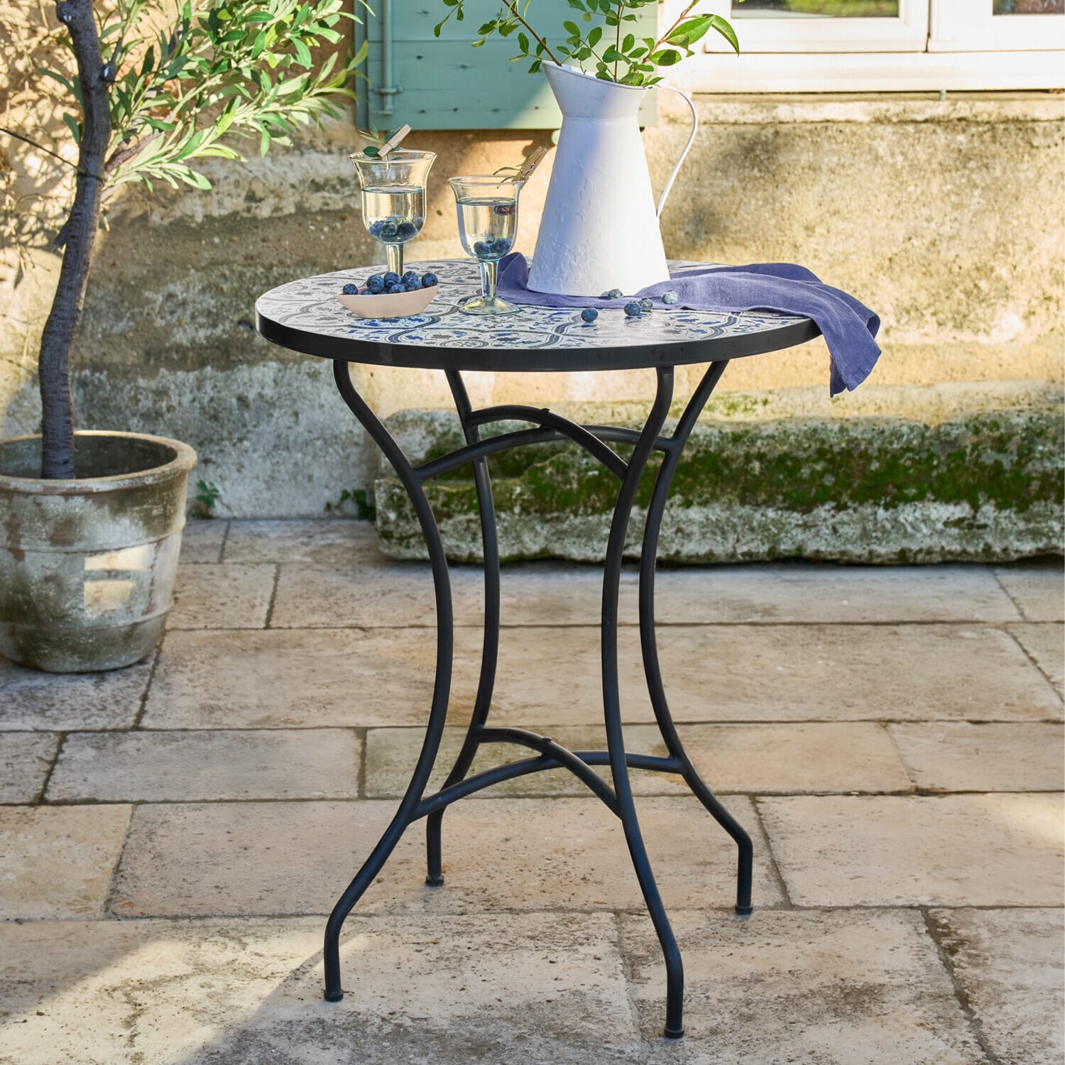 Stolek Giulessa Kulatý zahradní stůl s černou kovovou konstrukcí a modrobílou mozaikovou deskou na terase