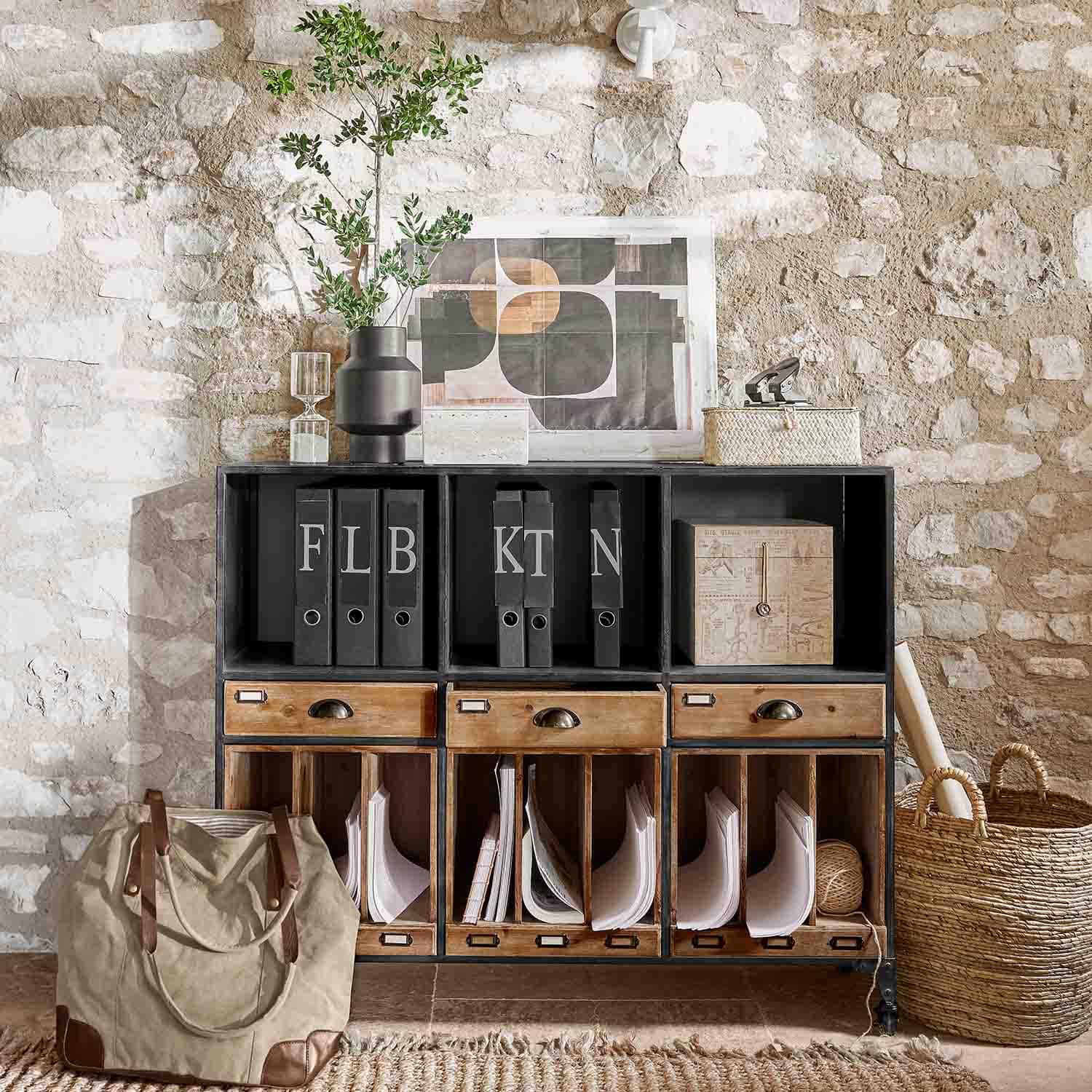 Černá kovovo-dřevěná komoda se zásuvkami a pořadači na pozadí kamenné zdi ve stylu loft