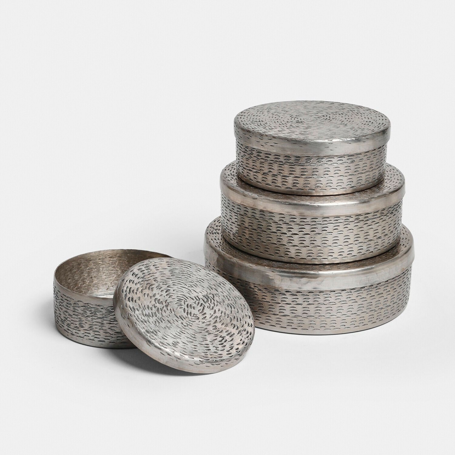 Sada tří kulatých kovových krabiček se stříbrným povrchem a texturovanými víčky