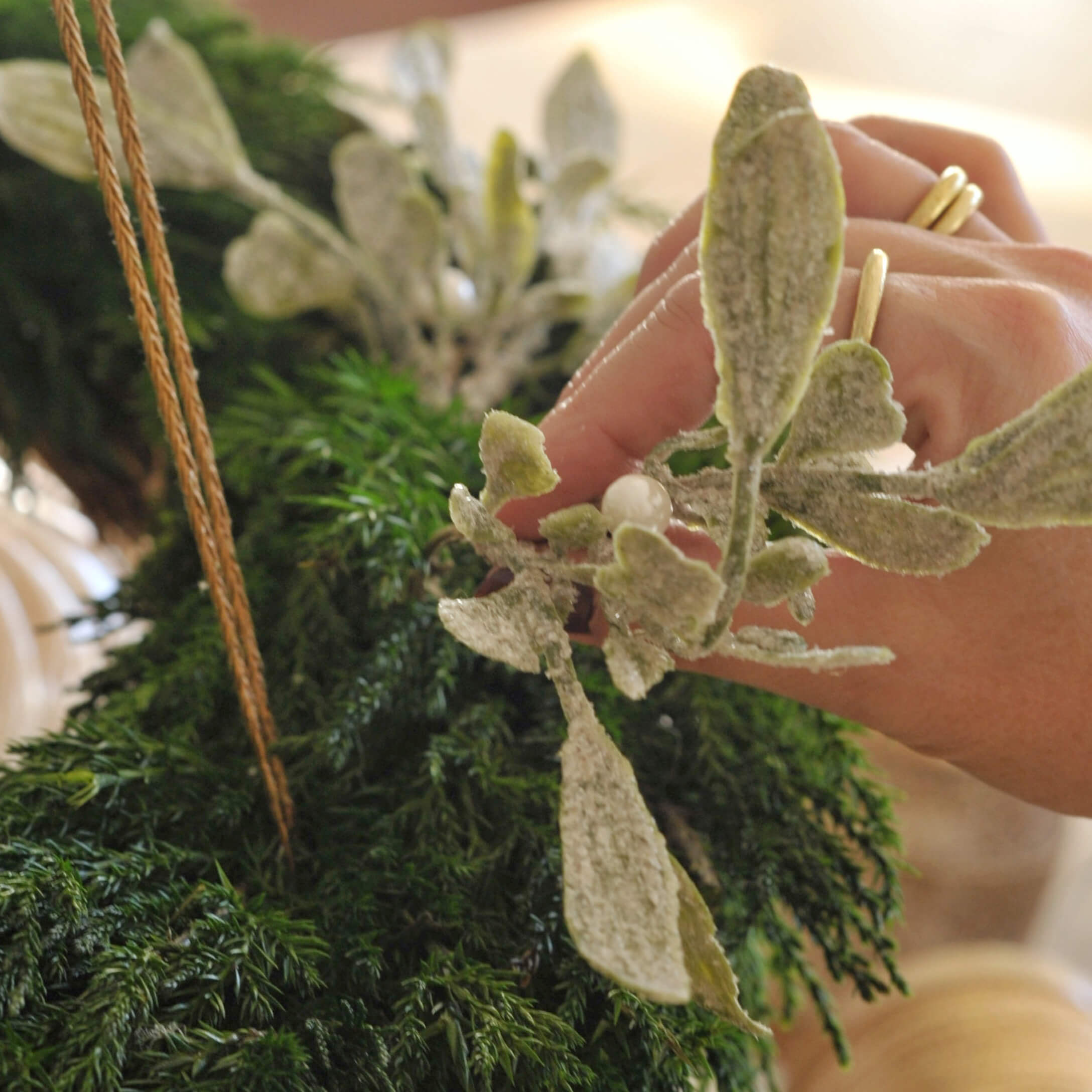 Bílý adventní věnec se zelenými větvičkami a umělým sněhem, vánoční dekorace