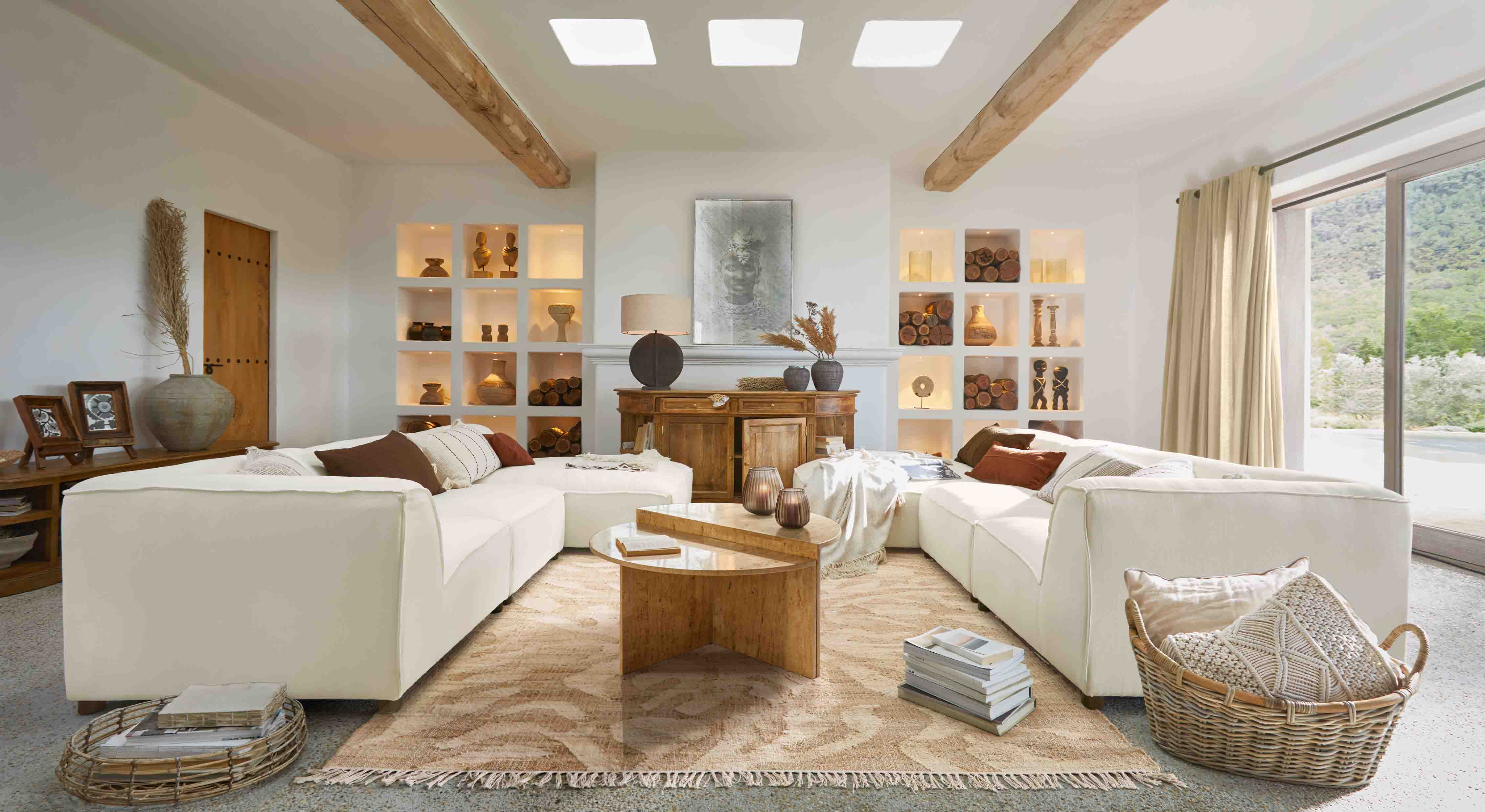 Prostorný obývací pokoj s bílou rohovou pohovkou, dřevěným stolkem a přírodními dekoracemi