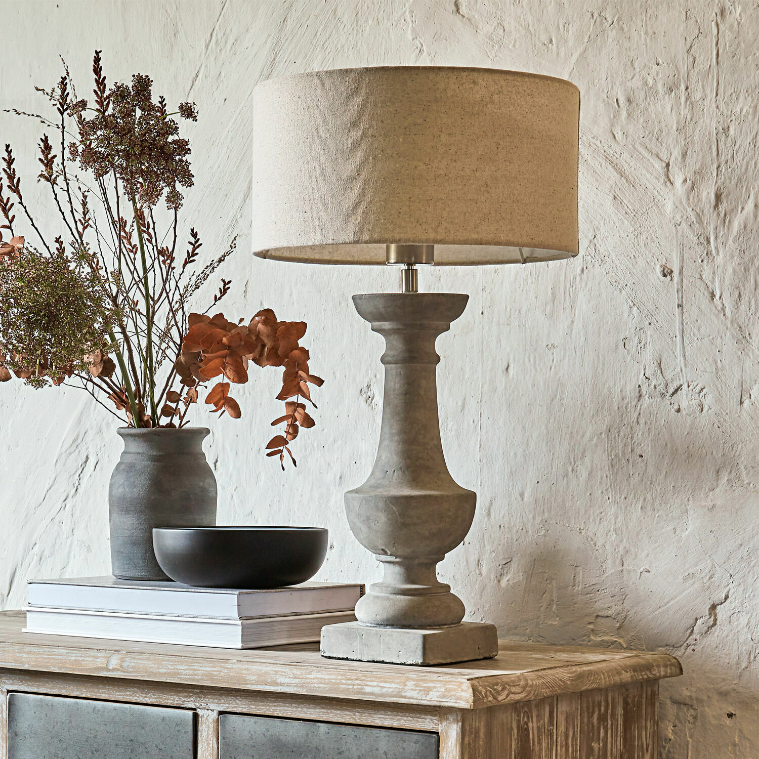 Stolní lampa Tifaine Stolní lampa z betonu s béžovým stínidlem na dřevěné komodě s dekorací