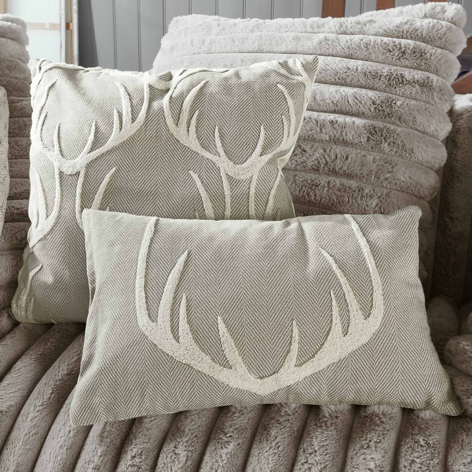 Béžové dekorativní polštáře s motivem paroží na měkkém plyšovém pozadí, bytový textil