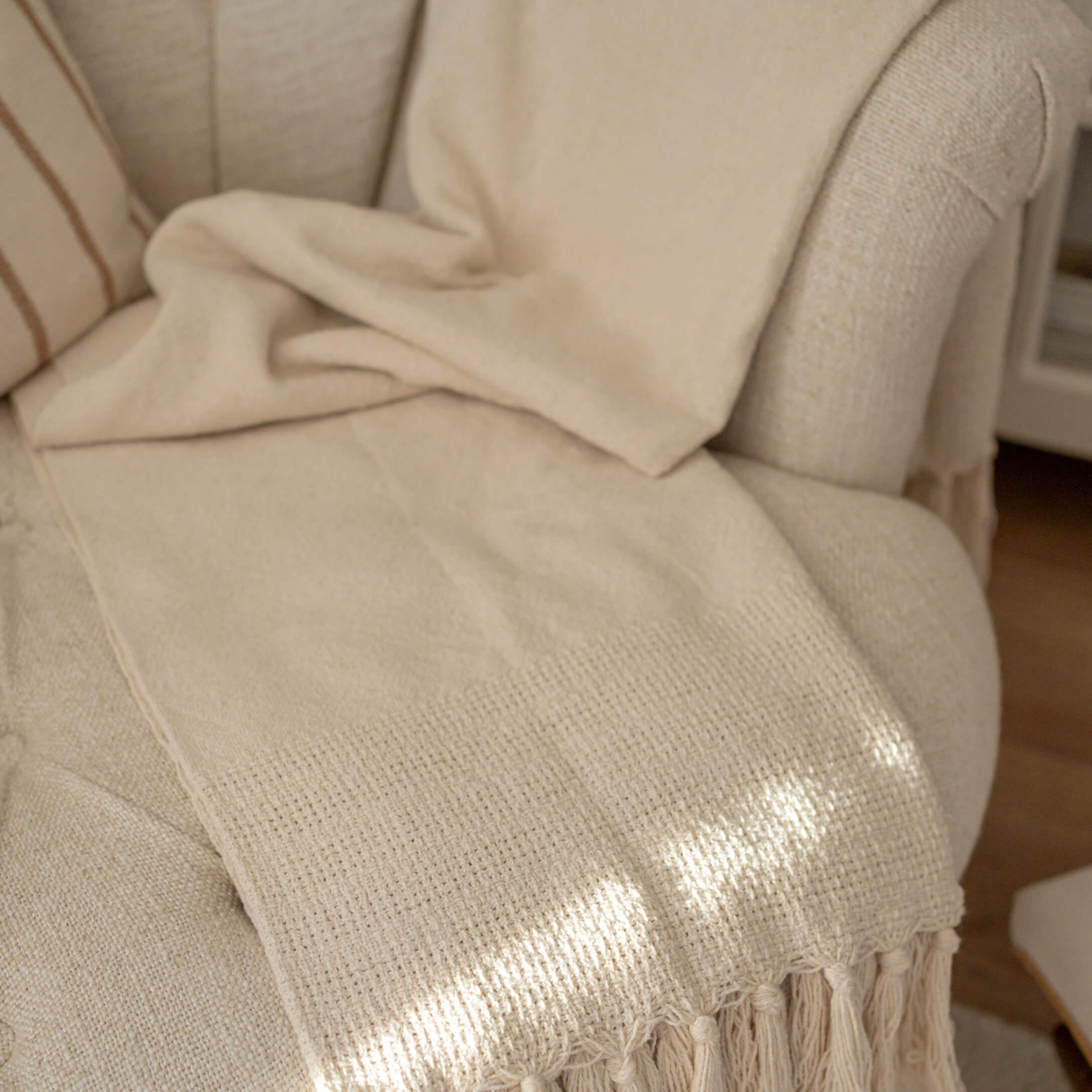Béžová deka s třásněmi na světlém křesle, měkký materiál pro dekoraci a odpočinek