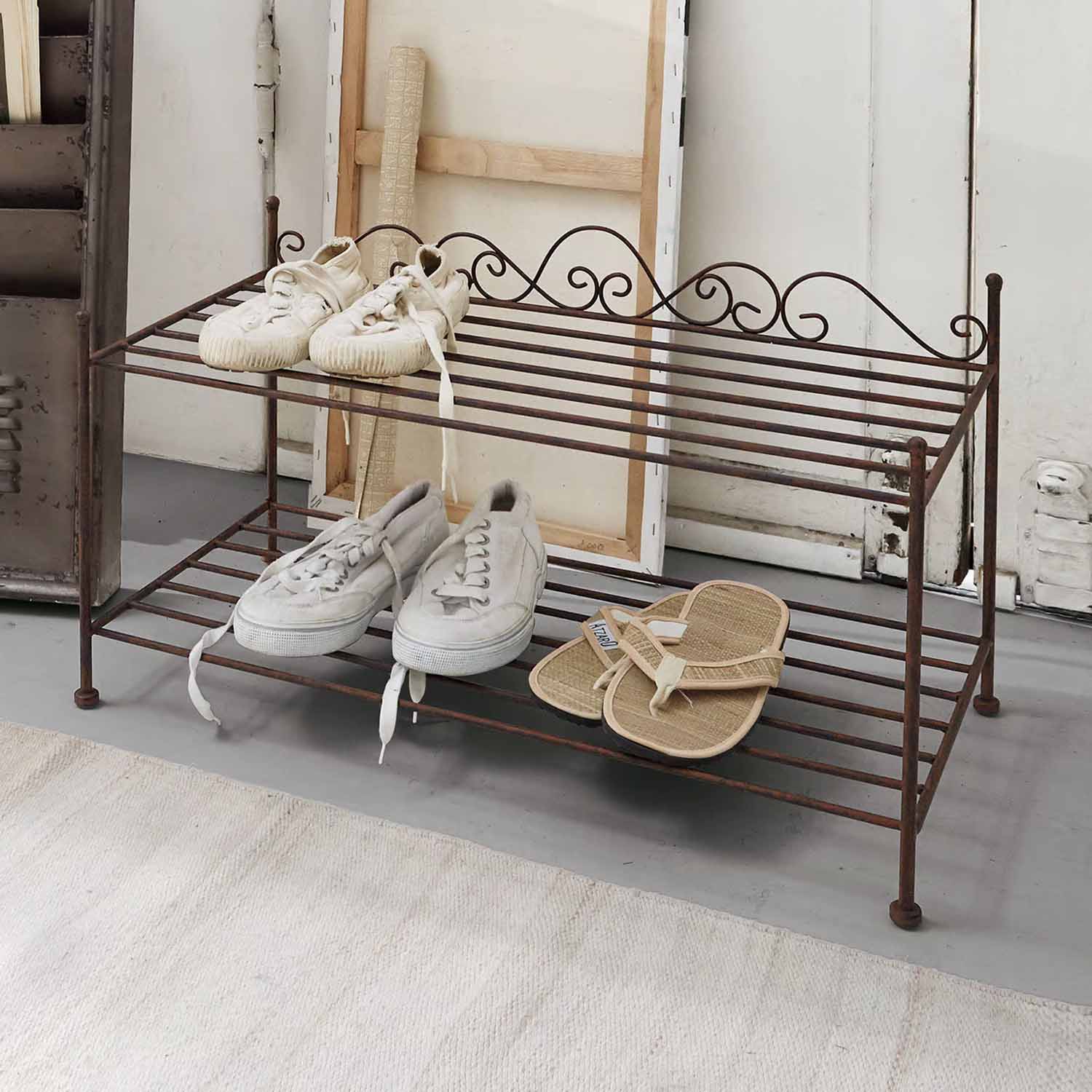 Dvoupodlažní kovový botník ve vintage stylu s bílými a béžovými botami s patinou rzi