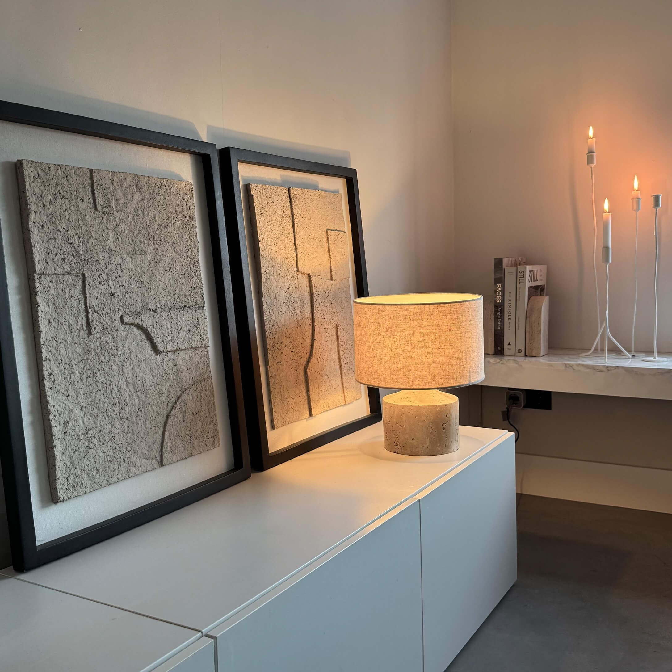 Moderní stolní lampa s béžovým stínidlem a kamenným podstavcem na bílé skříňce s texturovanou dekorací