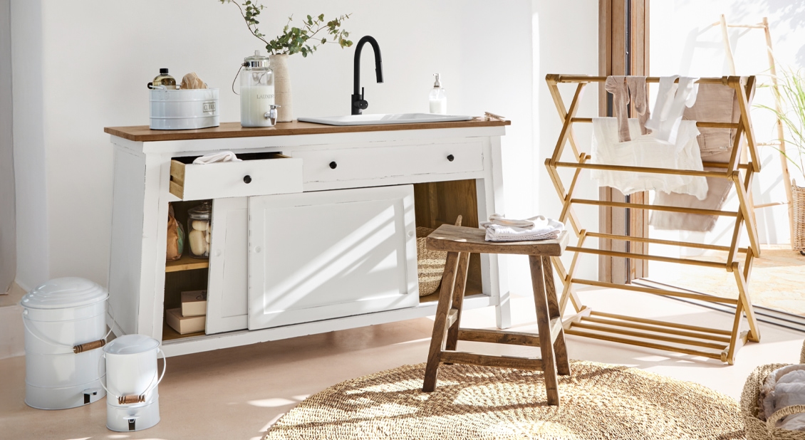 Světla koupelna s bílou dřevěnou skříňkou, černou baterií a přírodním dřevěným stolkem