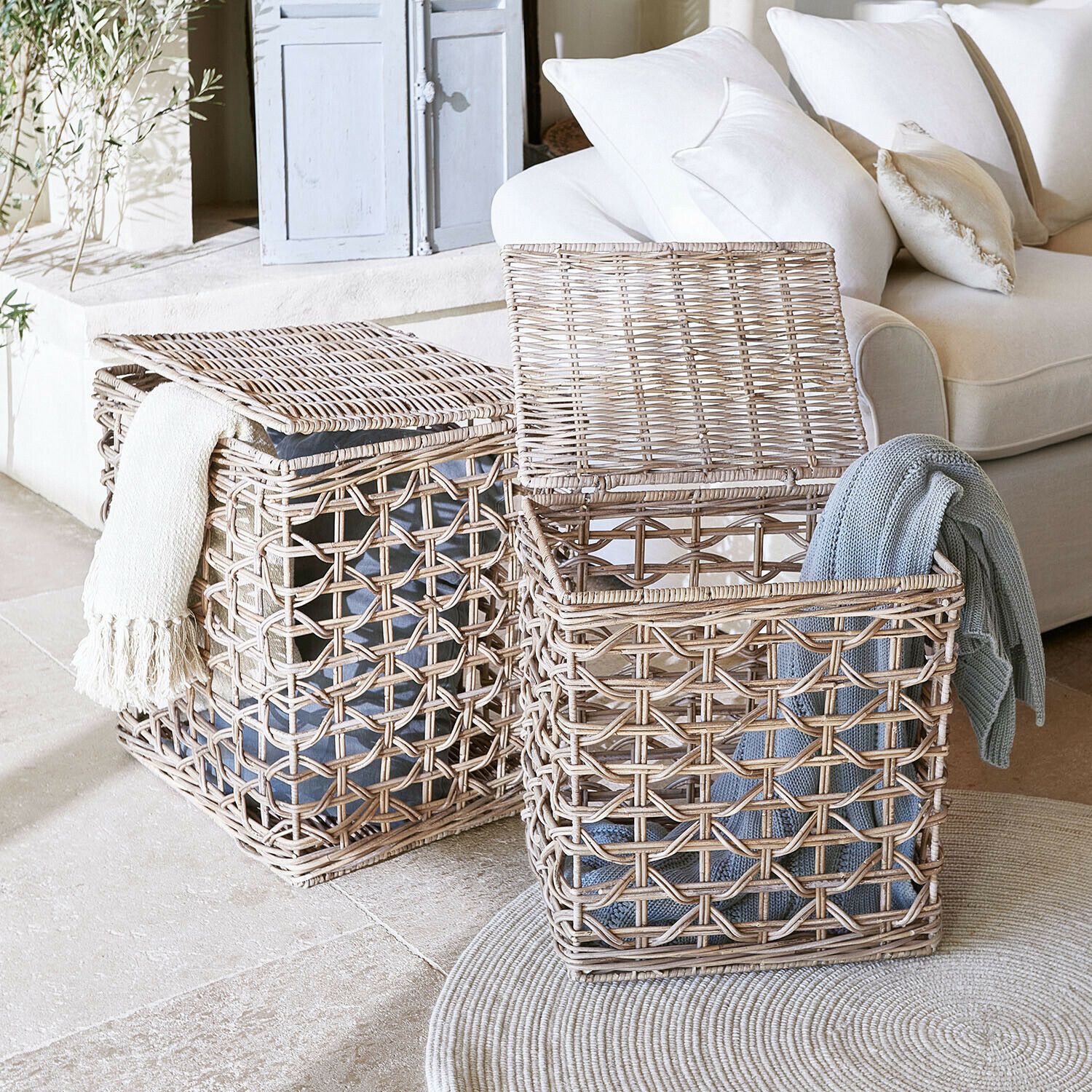 Dva proutěné koše na prádlo v přírodní barvě s dekami, praktické úložiště v obývacím pokoji