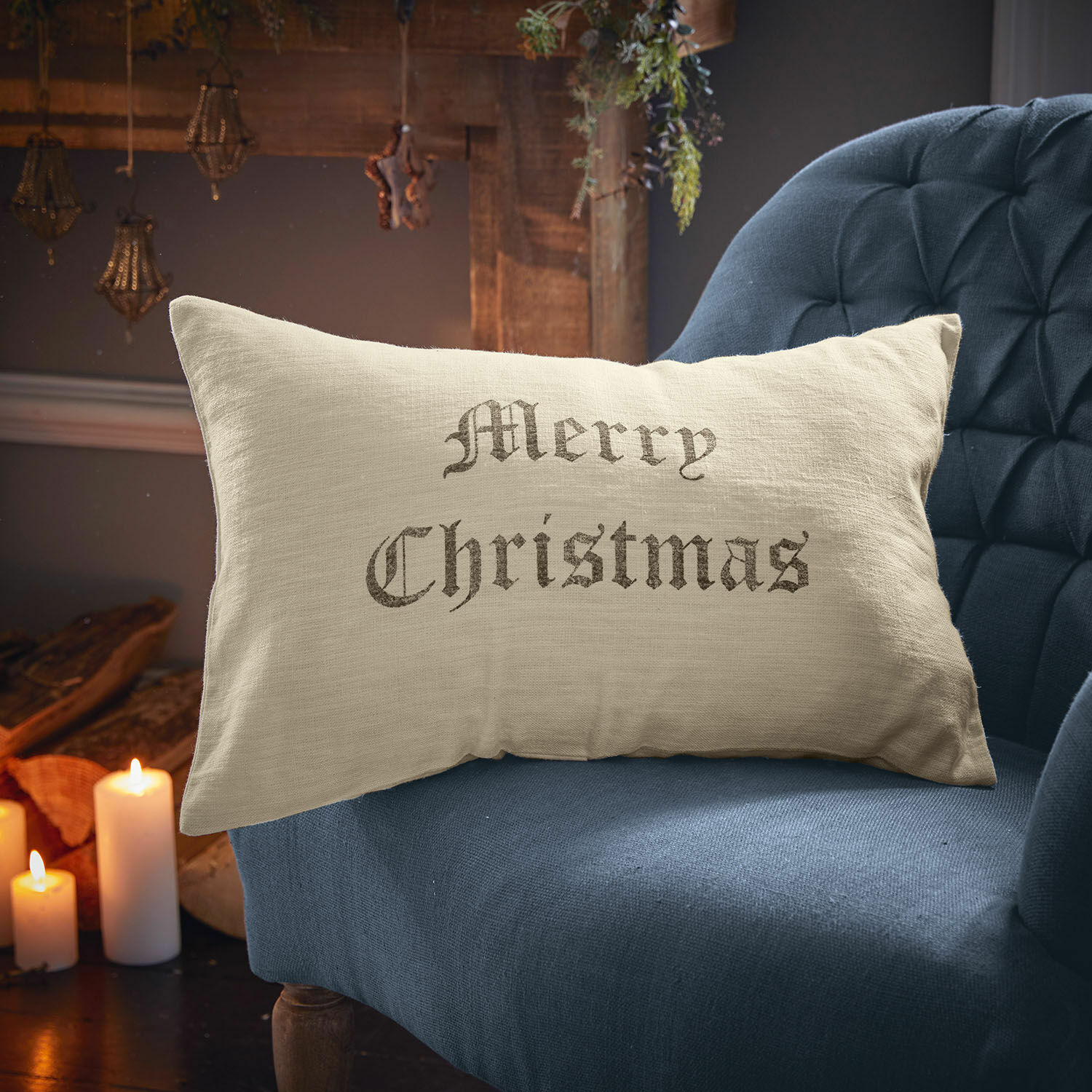 Povlak na polštářek Merry Christmas Béžový lněný polštář s nápisem Merry Christmas na modrém křesle, vánoční dekorace
