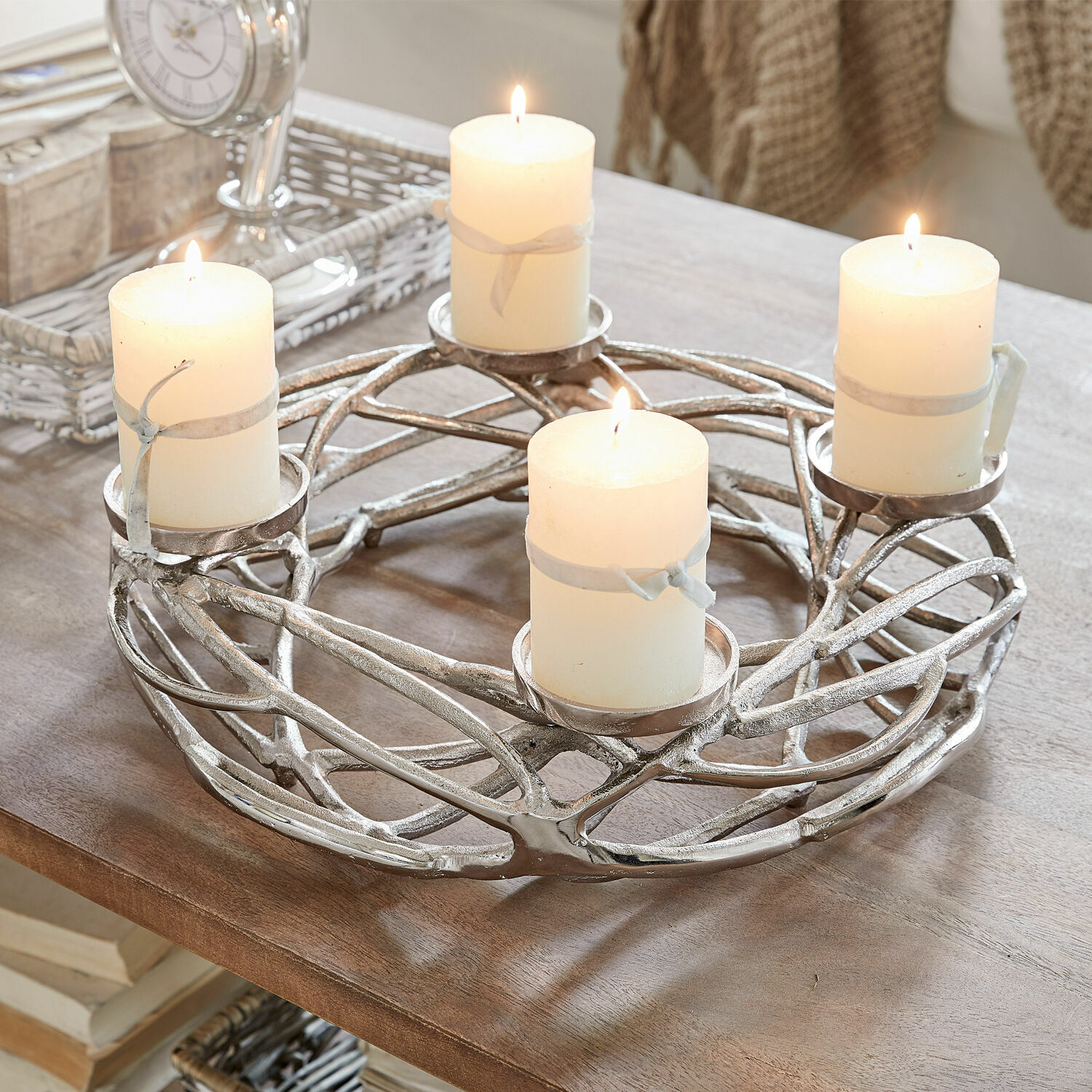 Věnec se svíčkami Coldfield Stříbrný kovový svícen se čtyřmi bílými hořícími svíčkami na dřevěném stole, interiérová dekorace