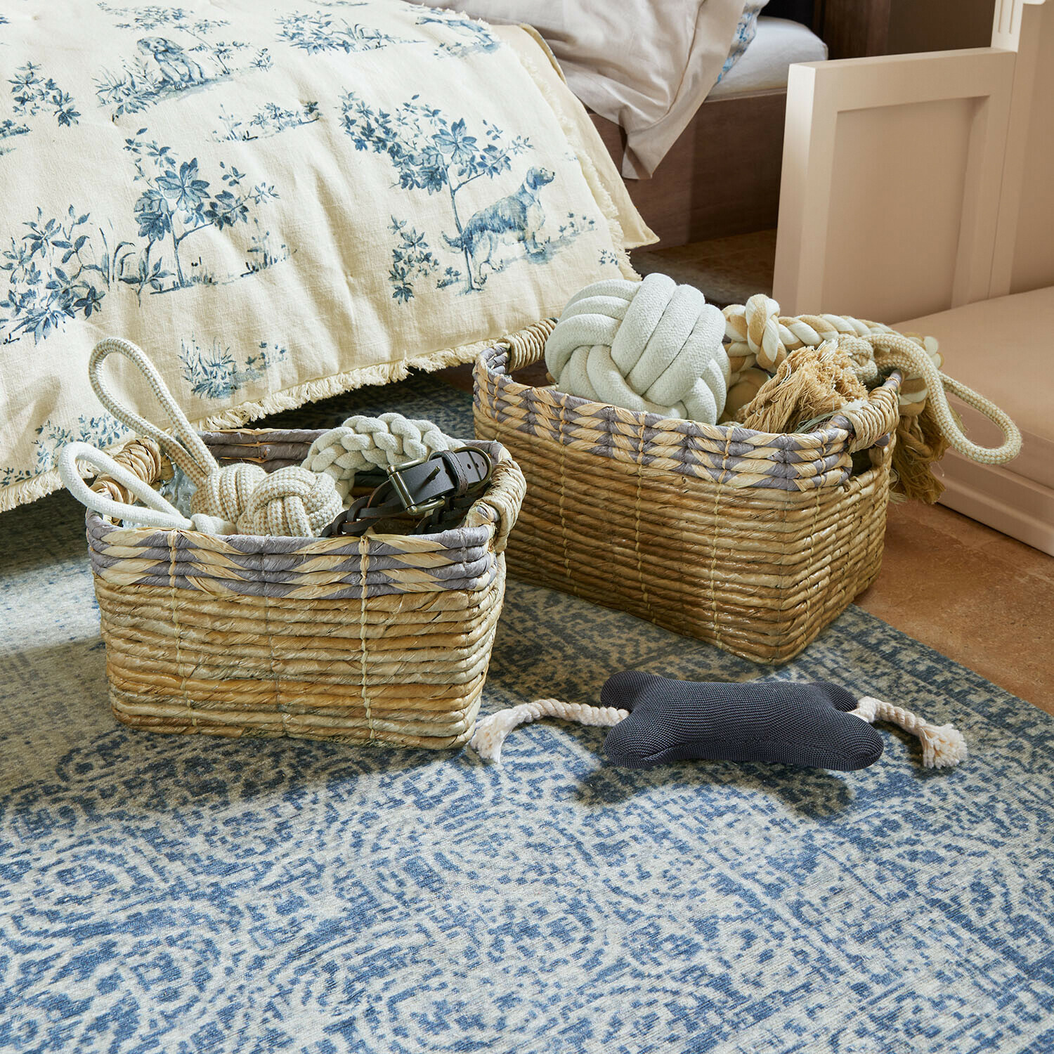 Dva proutěné koše s hračkami pro psy na modrém koberci v ložnici