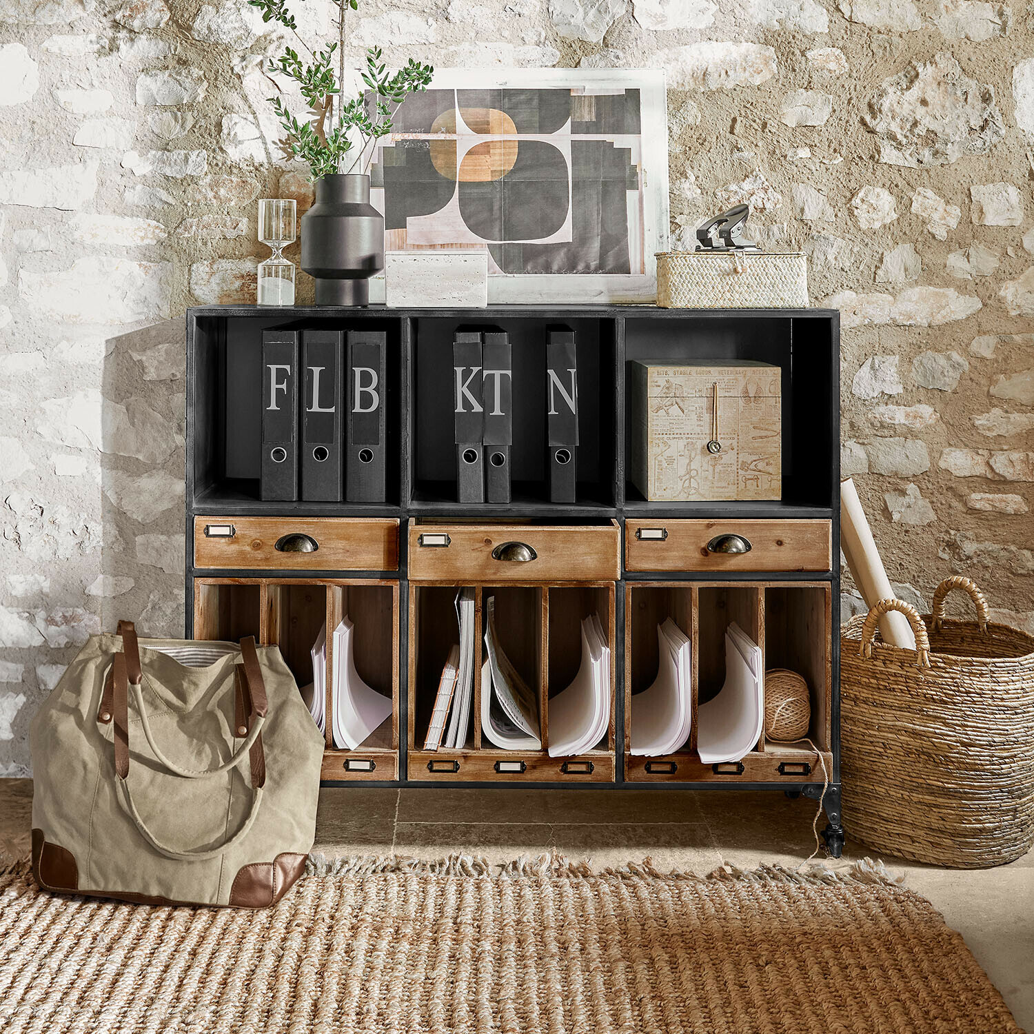 Černá kovovo-dřevěná skříňka se zásuvkami a pořadači před kamennou zdí ve vintage stylu