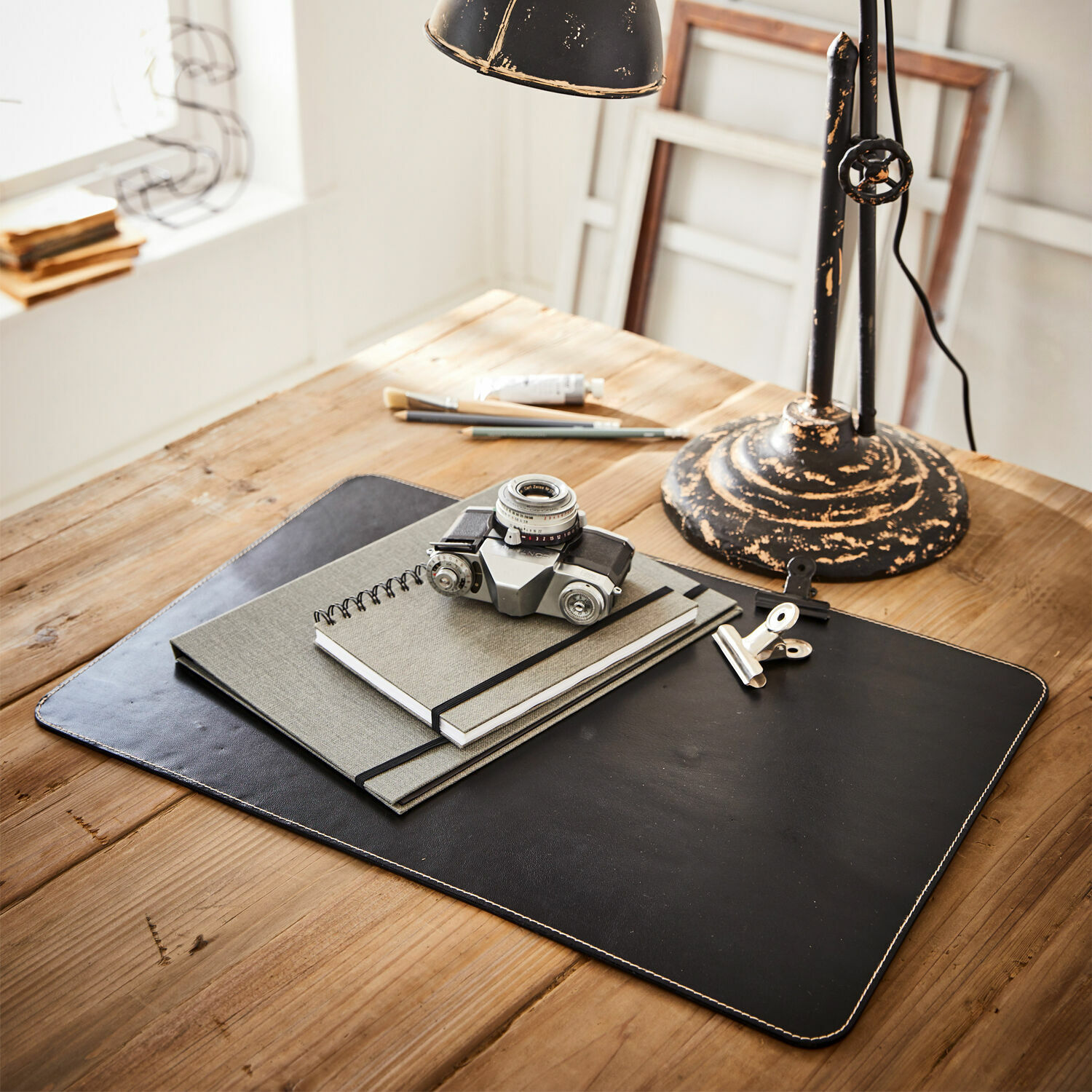 Podložka na psací stůl Jansen Černá kožená podložka na stůl s poznámkovými bloky a starým fotoaparátem na dřevěném stole