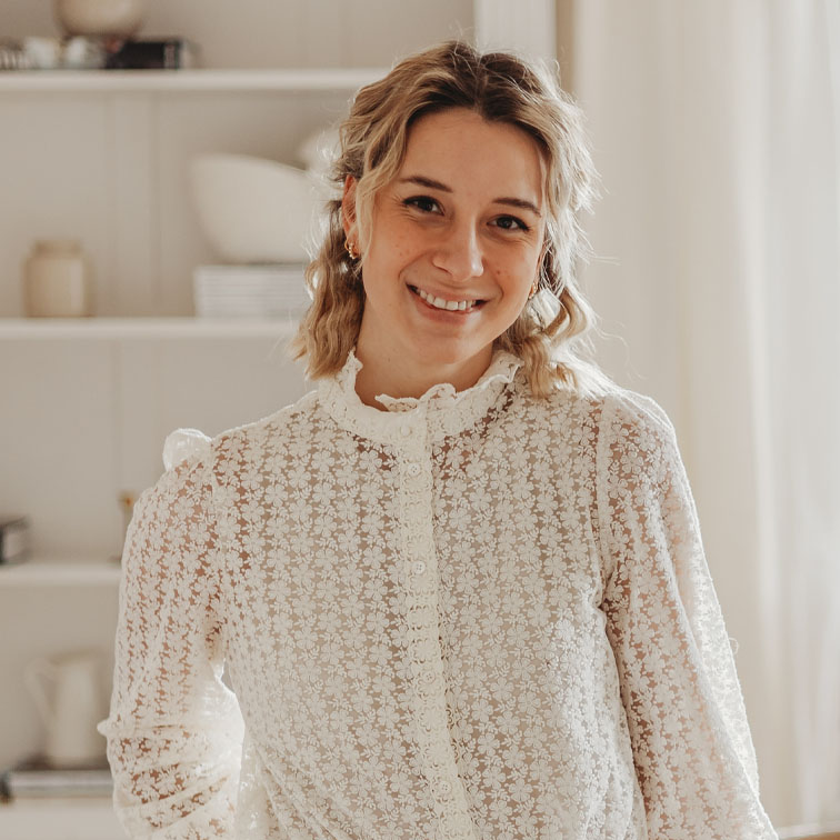 Žena v bílé krajkové blůze s květinovým vzorem v světlém domově
