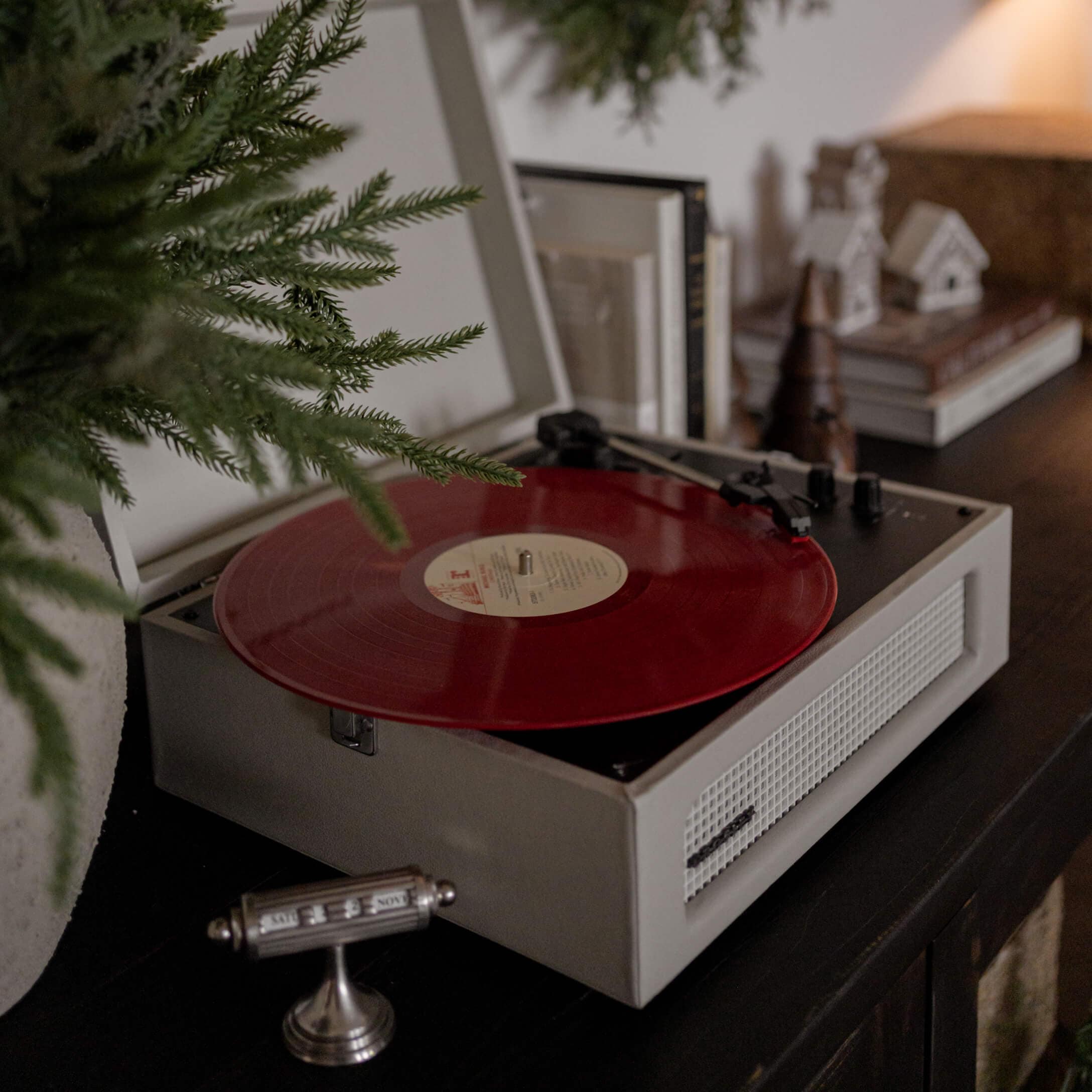 Retro gramofon s červenou vinylovou deskou na tmavém nábytku v útulném interiéru